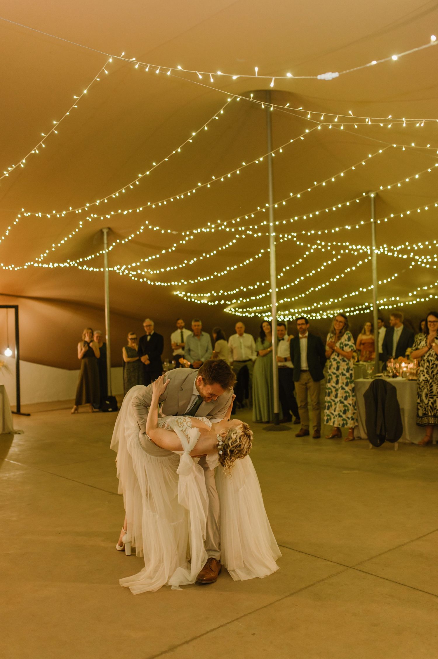 Romantic dance sequence under twinkling lights in a wedding reception tent.