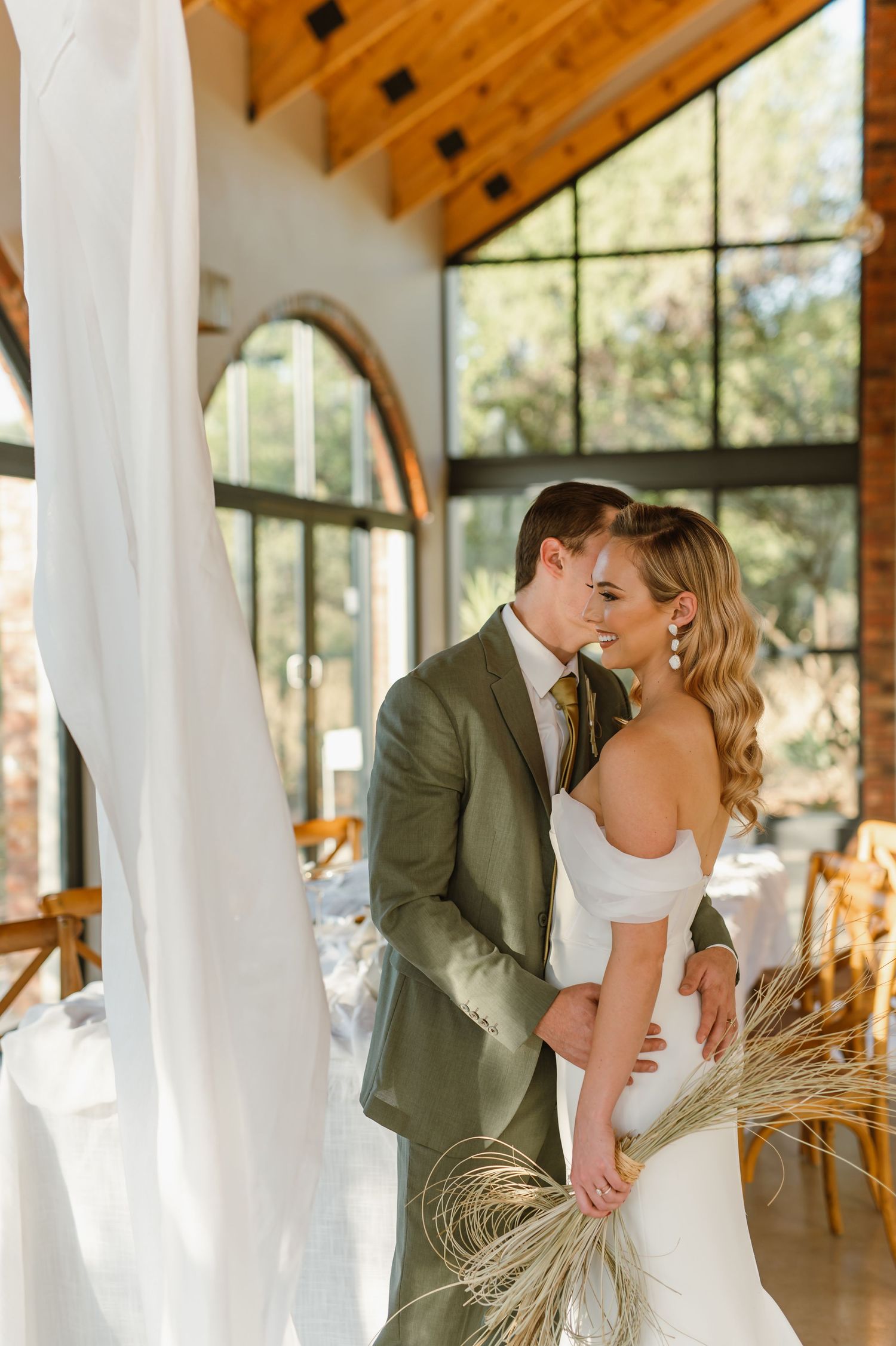 Romantic wedding portrait in a modern venue with large windows and natural lighting.