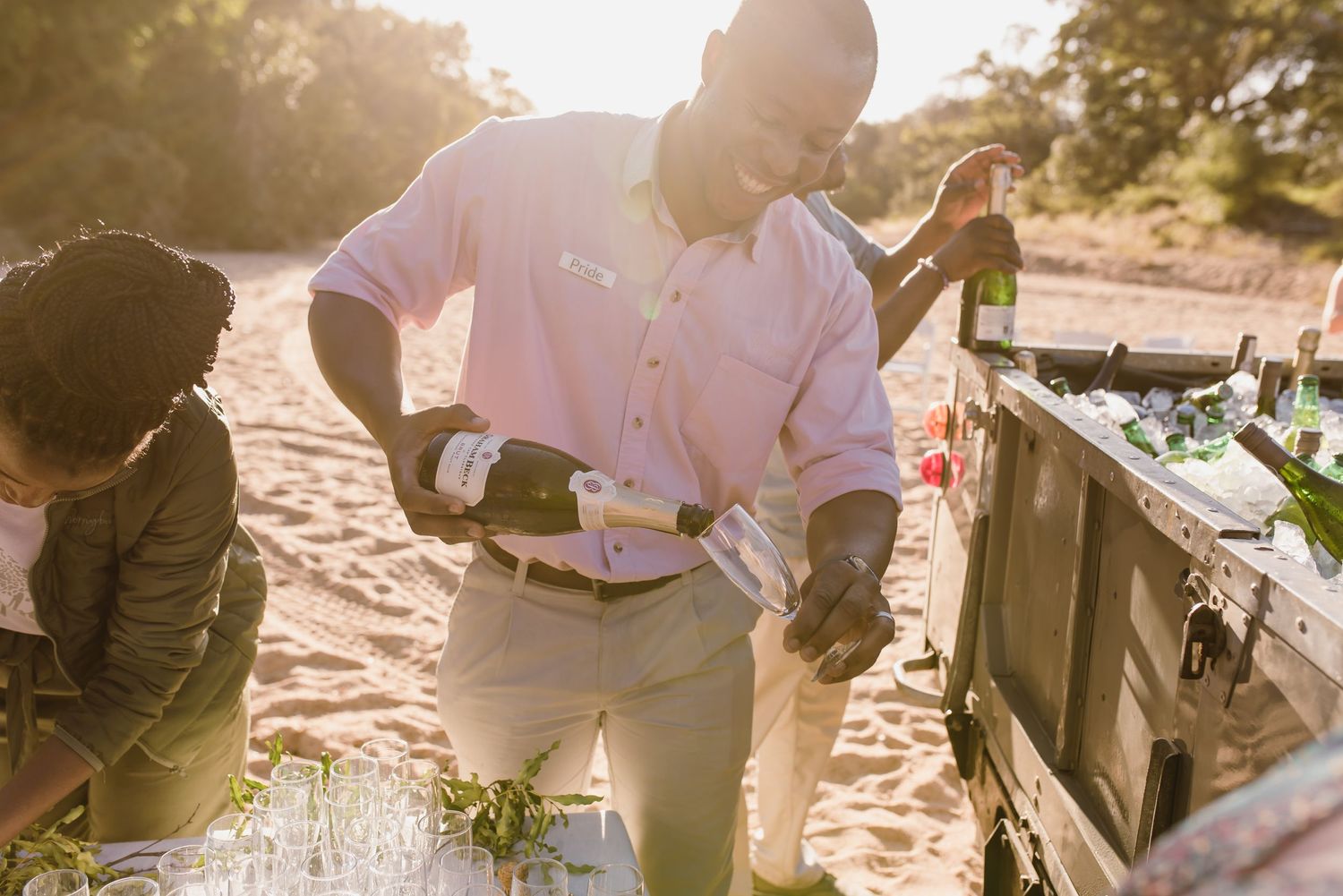 Guests enjoying refreshments at an outdoor beach wedding reception during golden hour.