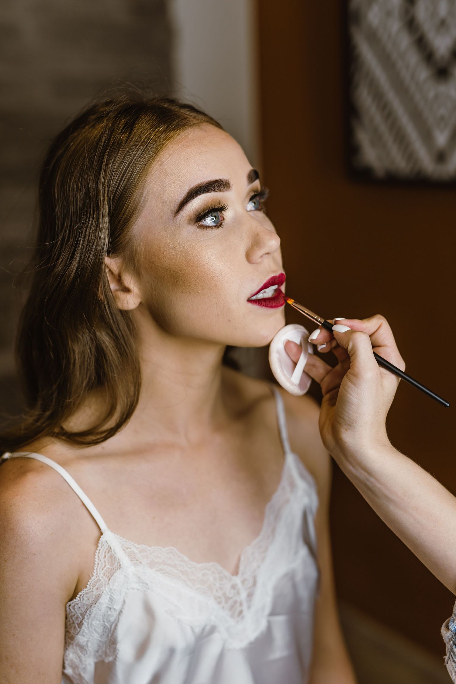 Bridal preparation scene showing makeup application in soft natural light.