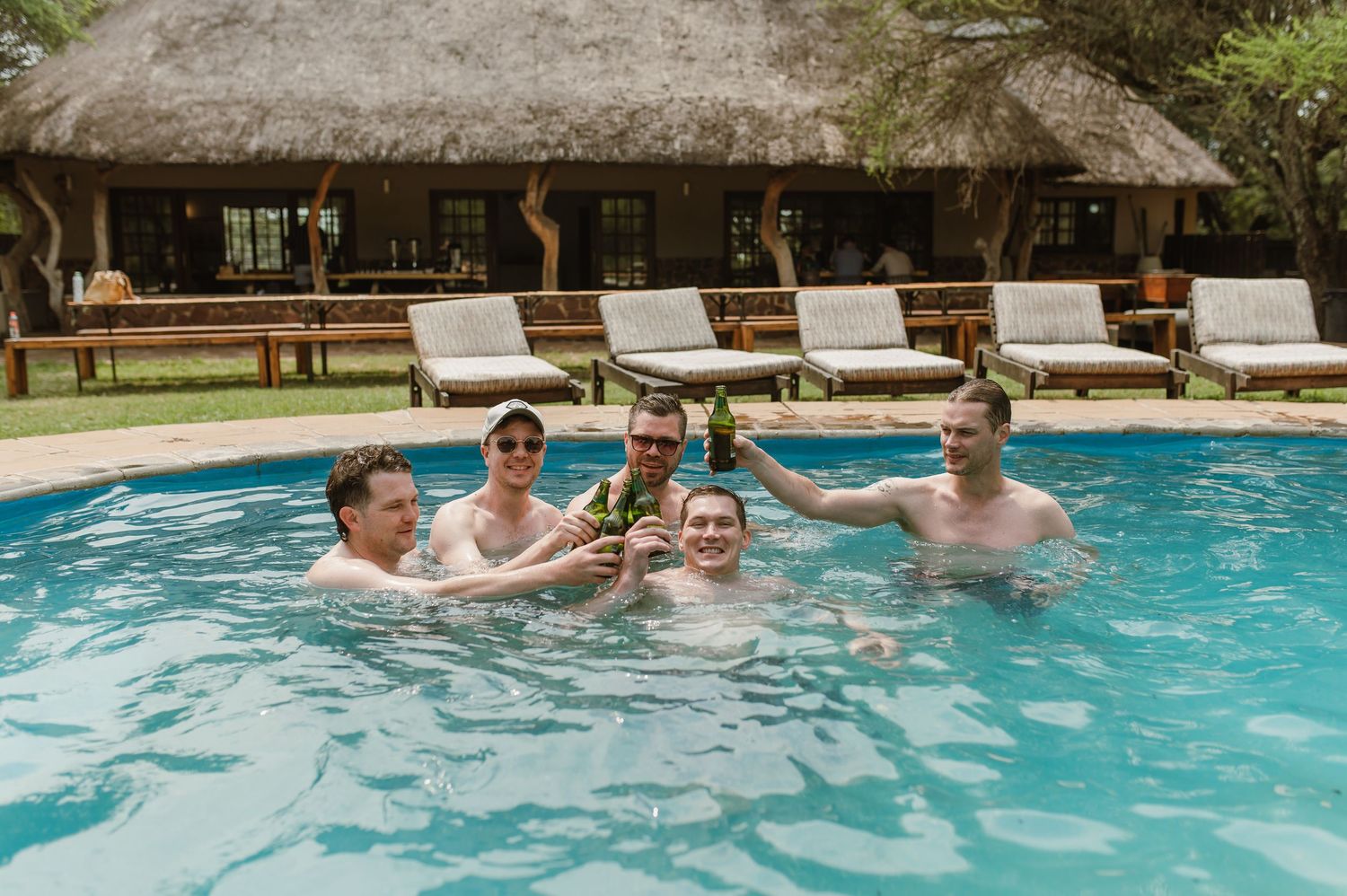 A group of people enjoying a refreshing swim and playing together in a bright blue swimming pool on a sunny day.