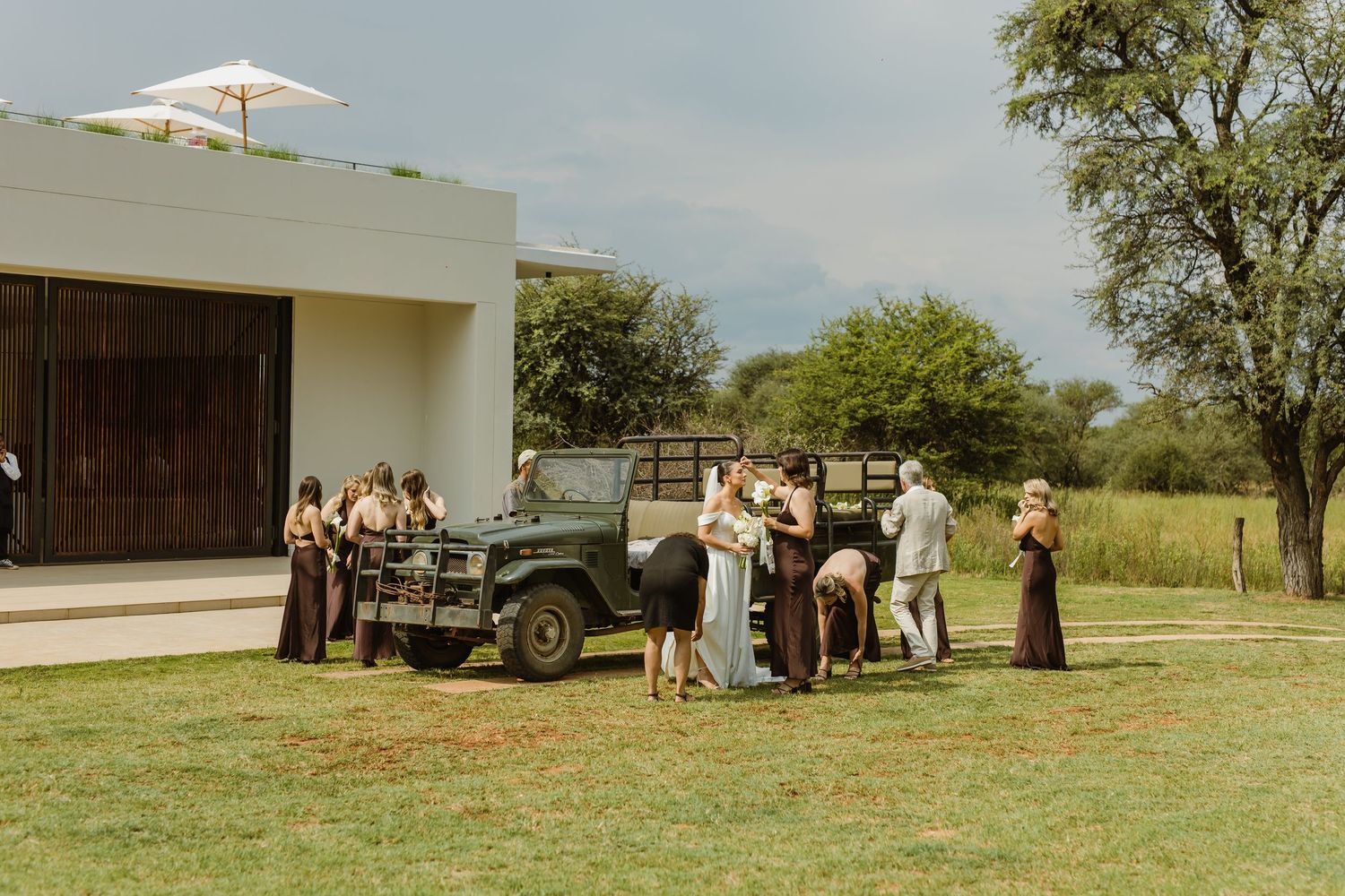 Contemporary white building with umbrella parasols and guests gathered on a grassy landscape.