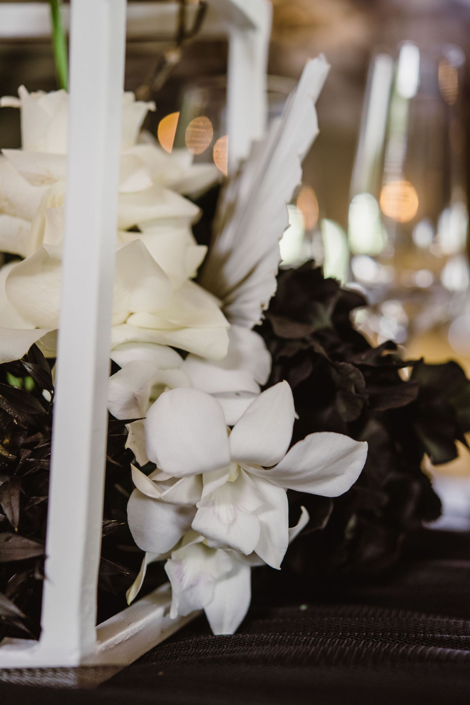 White and black floral arrangements with candles creating an elegant table centerpiece.