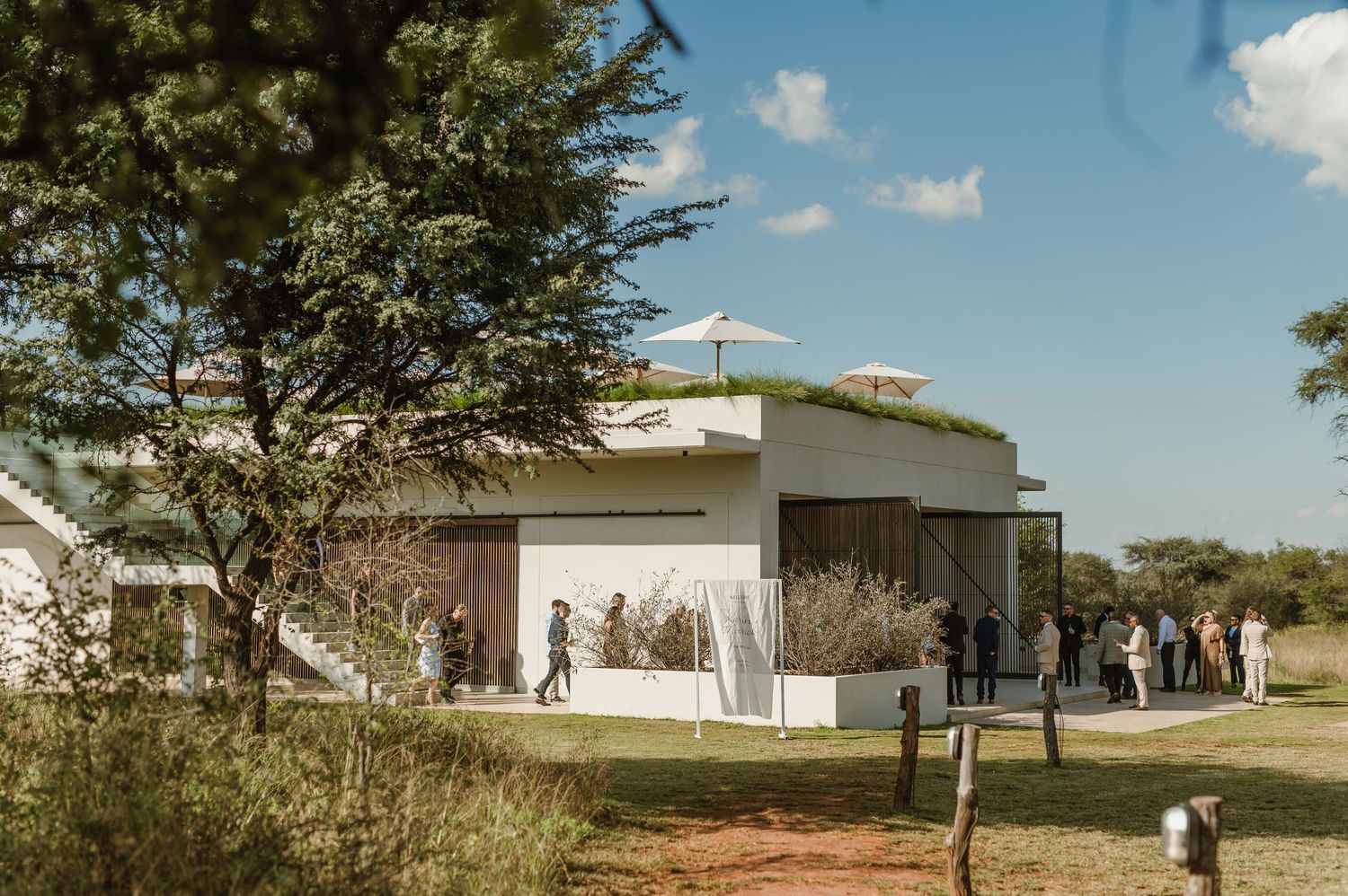 Modern white wedding venue buildings set against blue sky with scattered clouds.