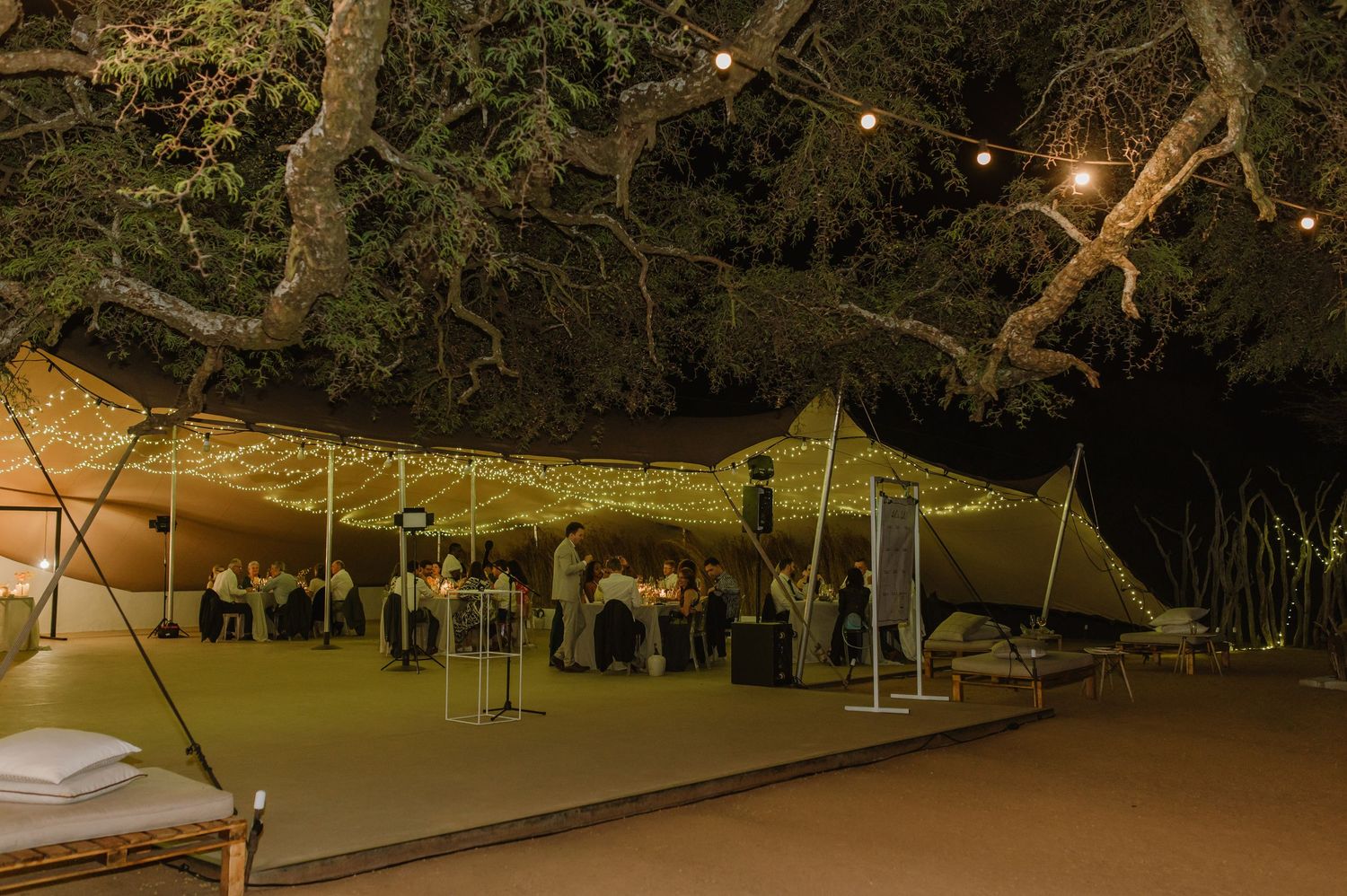 Outdoor wedding venue at night with illuminated tents and trees creating a magical atmosphere.