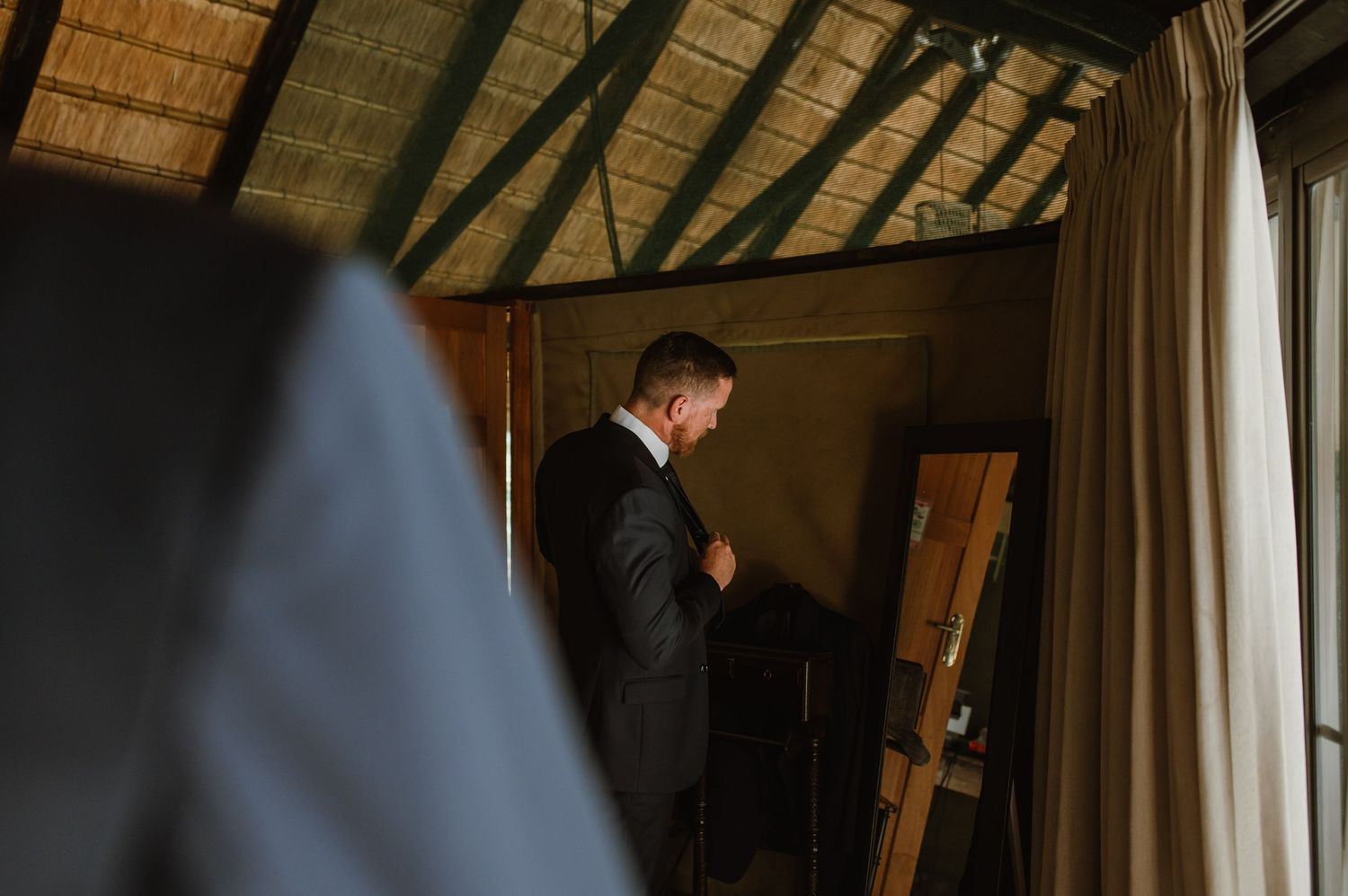 Silhouettes of groomsmen preparing in a cabin with dramatic lighting.