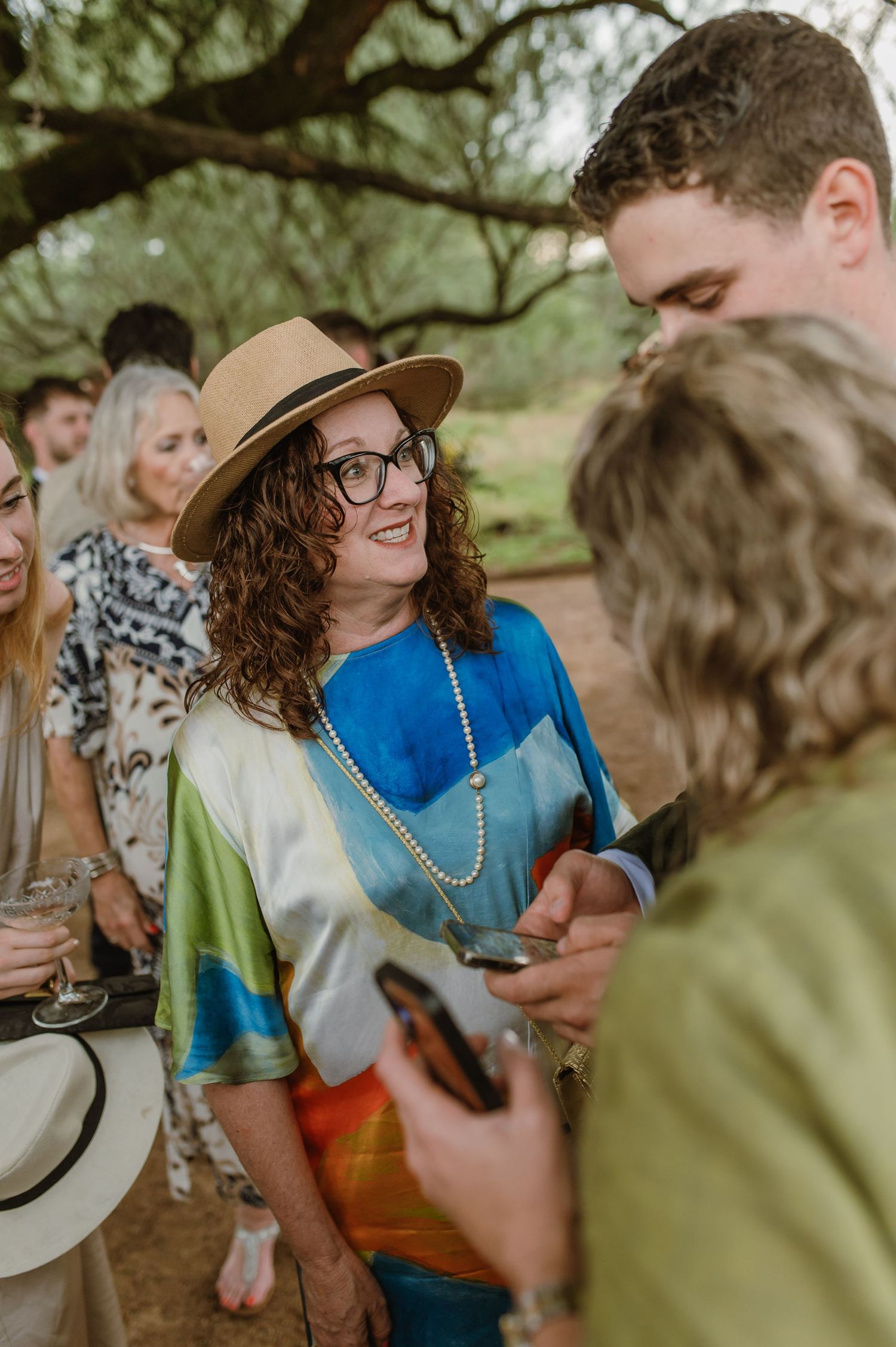 Wedding guests in colorful attire mingle during outdoor celebration.