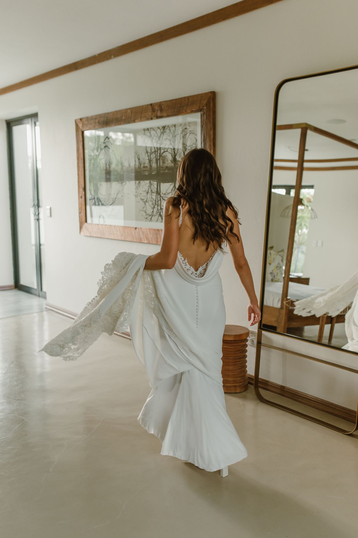 Dancing figure in white spins through a bright corridor with wooden trim and mounted artwork.