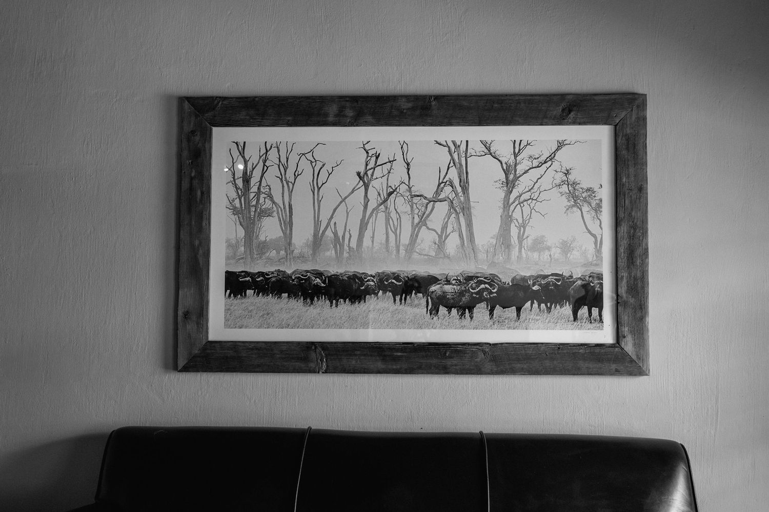 Long panoramic artwork of winter trees and wildlife displayed above dark furniture.