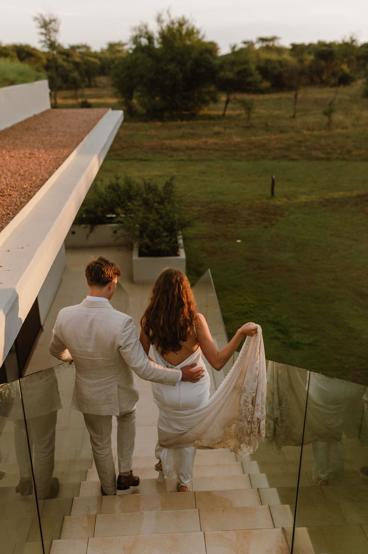 A couple descends white stairs together at sunset during their wedding.