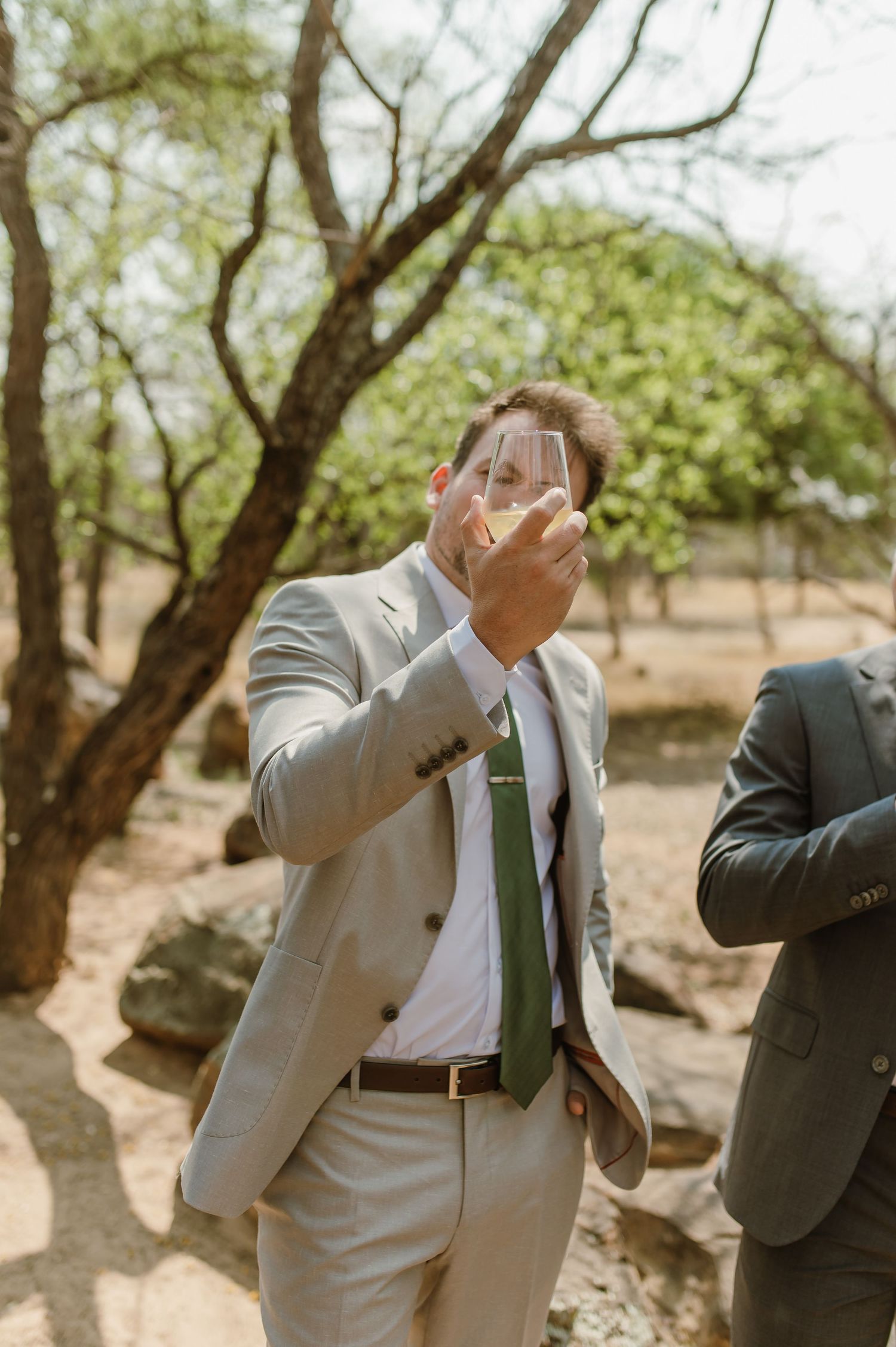 Men in formal attire taking shots of liquor in an outdoor setting.