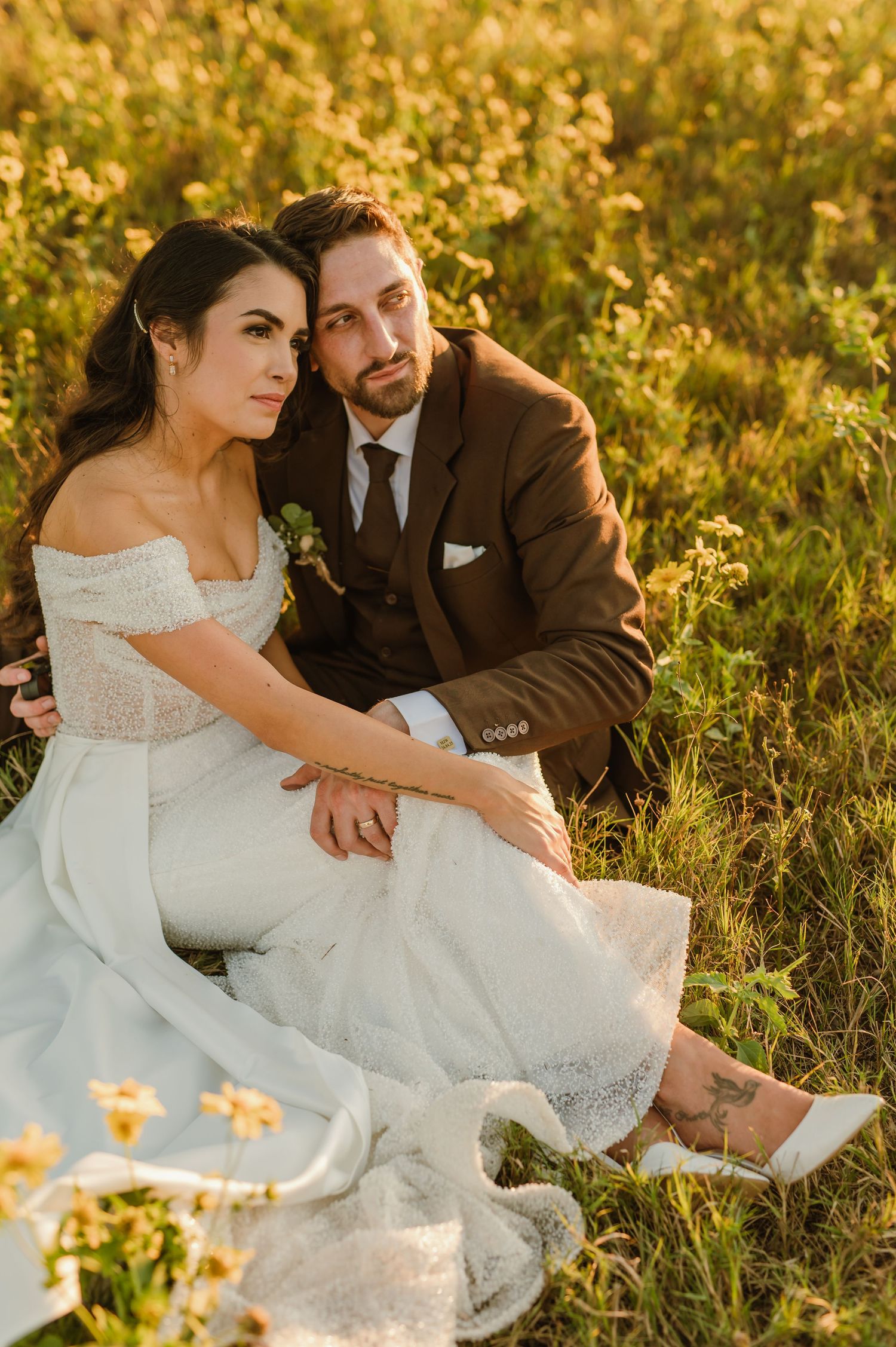 An intimate wedding portrait amidst golden wildflowers during sunset with soft natural lighting.