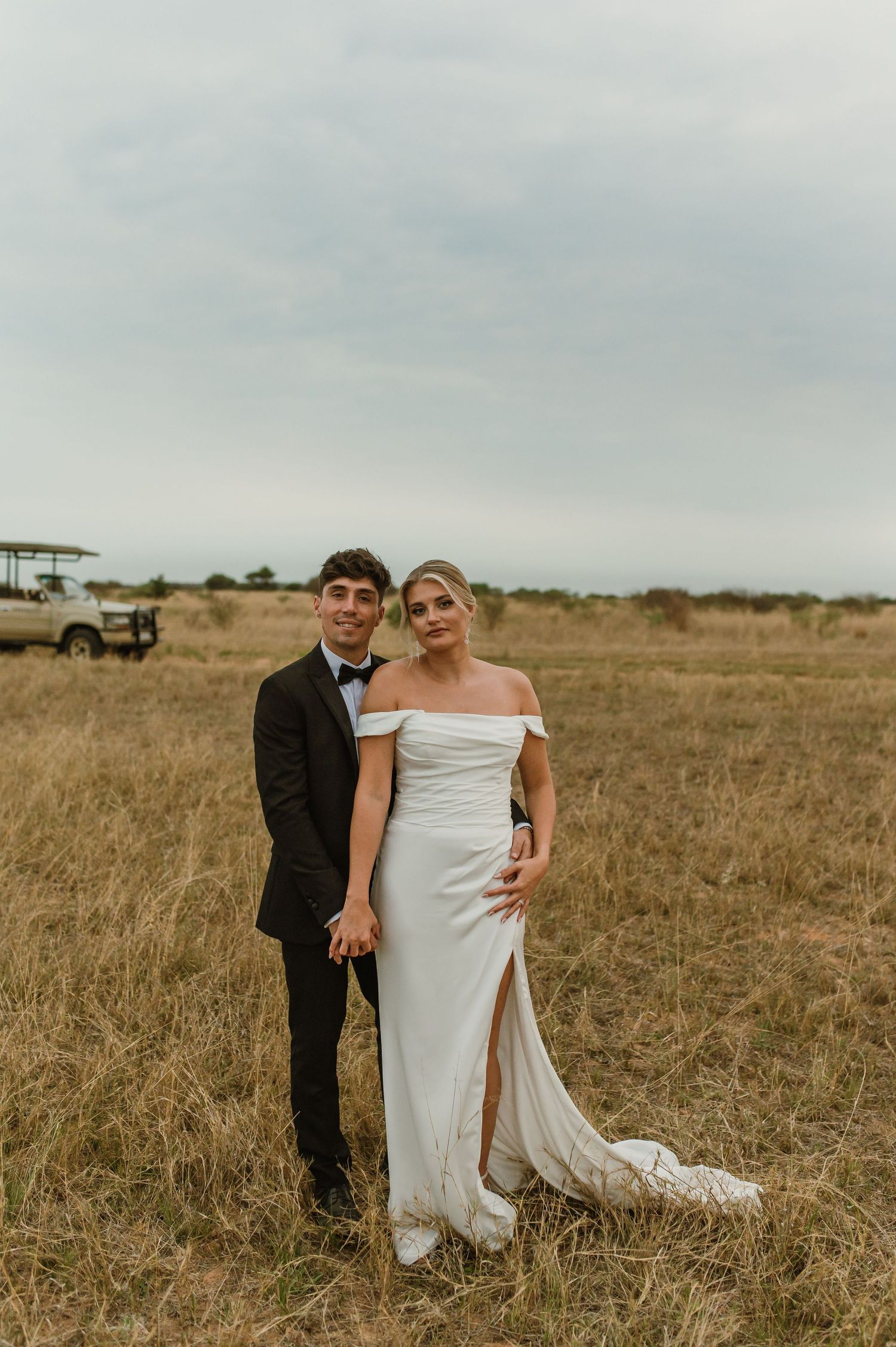 Wedding couple shares playful moment in rustic outdoor setting.
