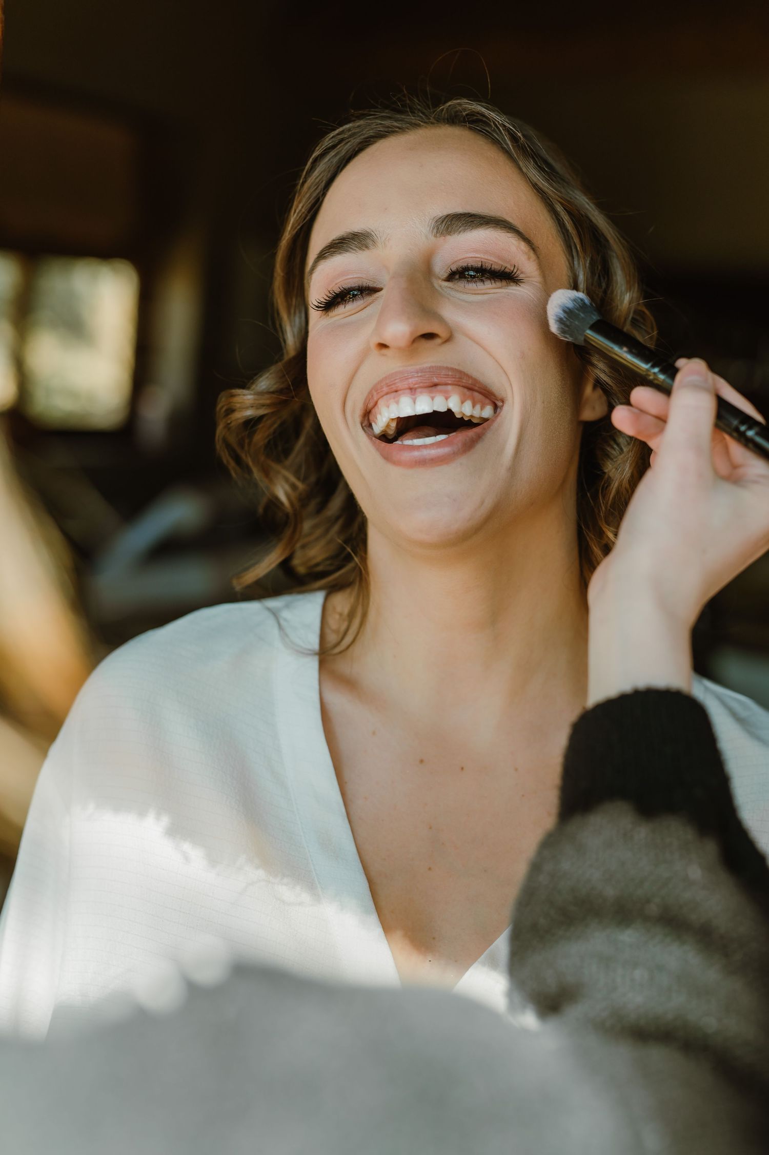 Close-up of makeup application with brush in warm natural lighting.