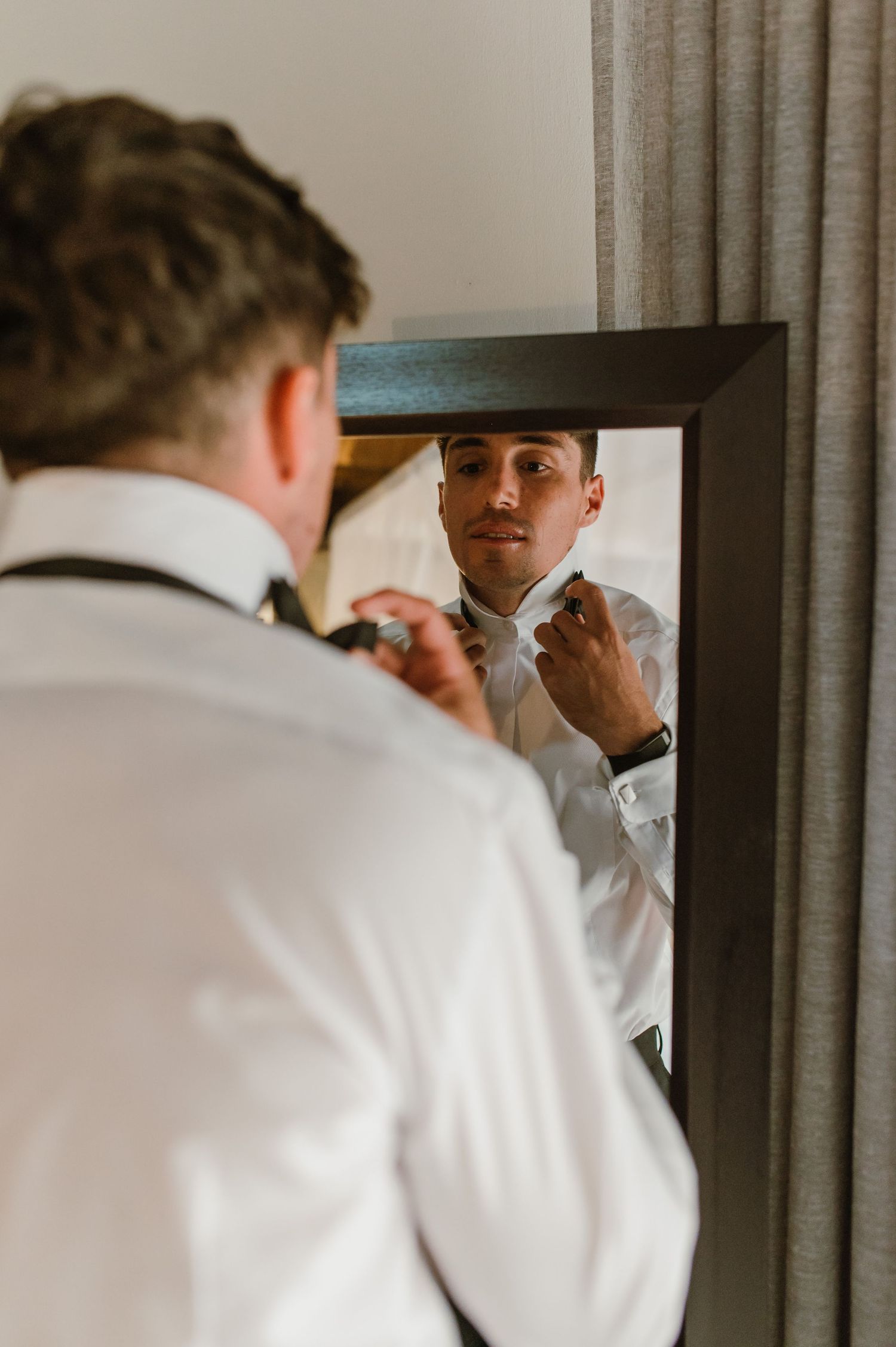 Reflection in mirror shows formal attire preparation with white shirts and ties.