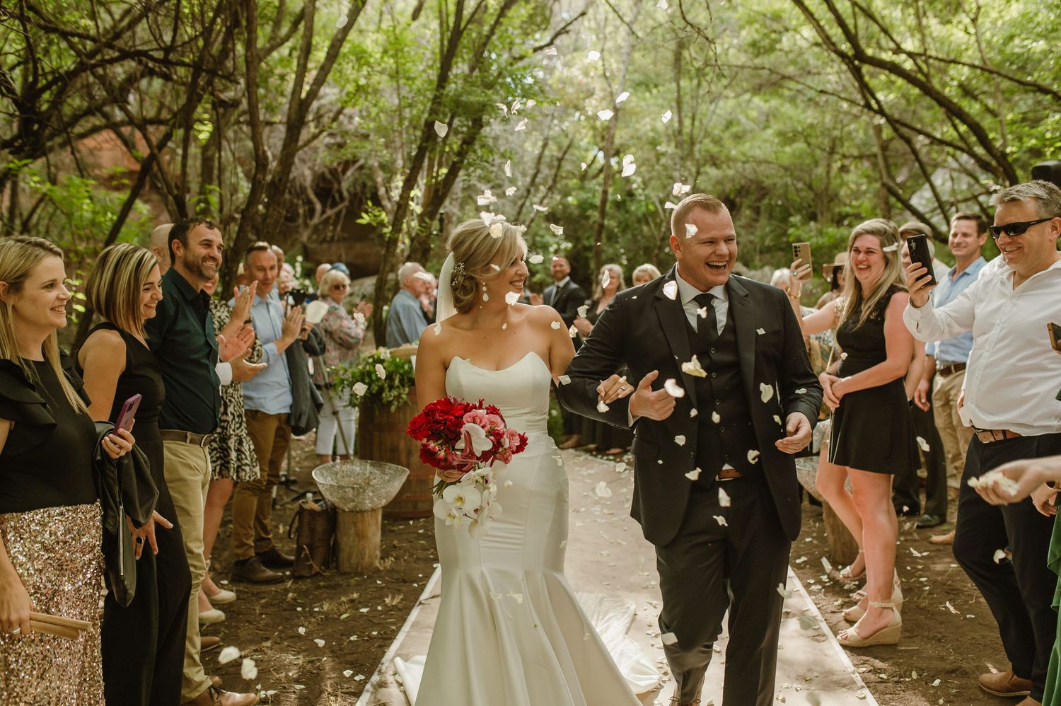 Wedding party and guests celebrating on a rustic woodland path with natural lighting.