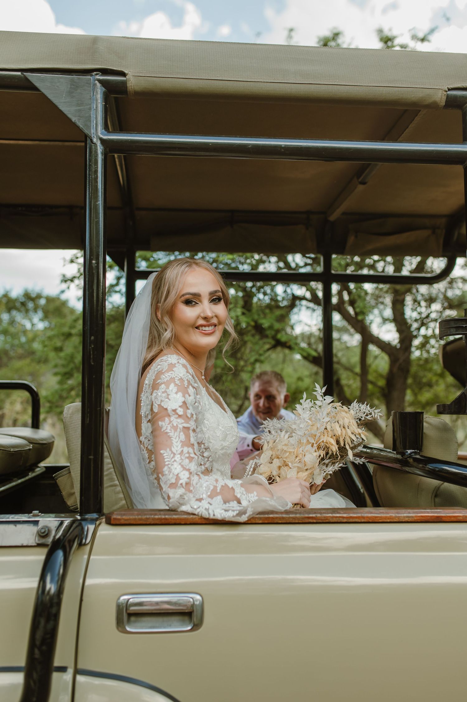 Vintage cream-colored safari vehicle parked at outdoor wedding venue.
