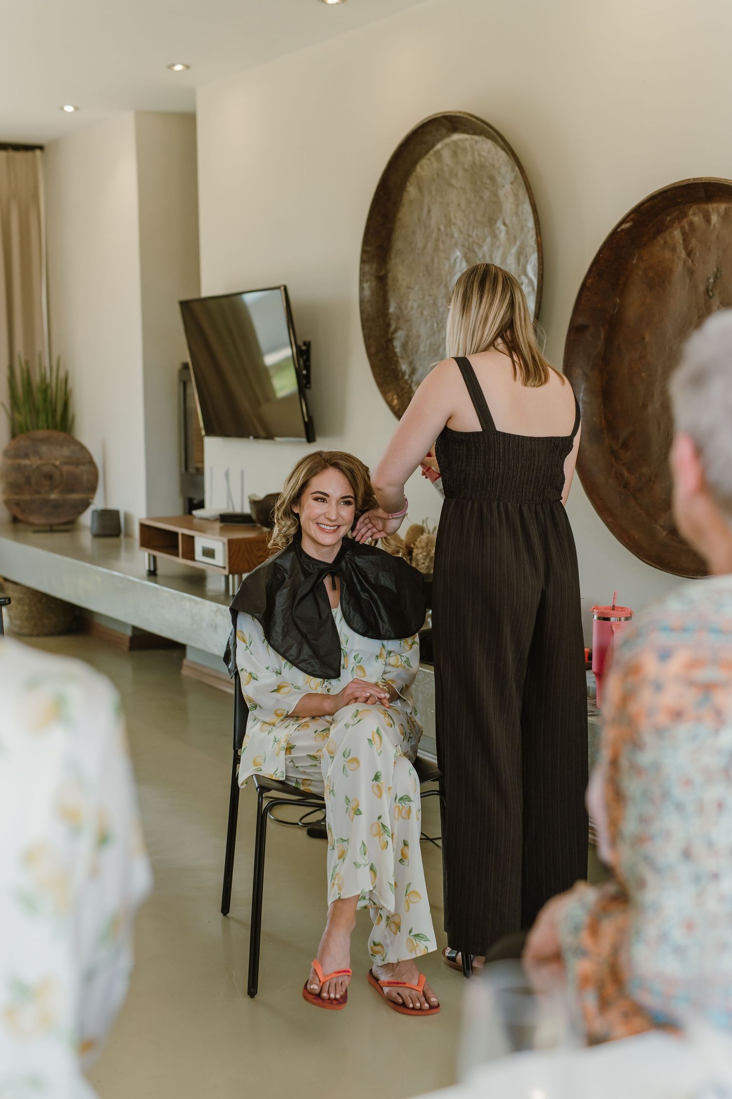 Wedding preparation scene with dresses and attendants in a contemporary room.