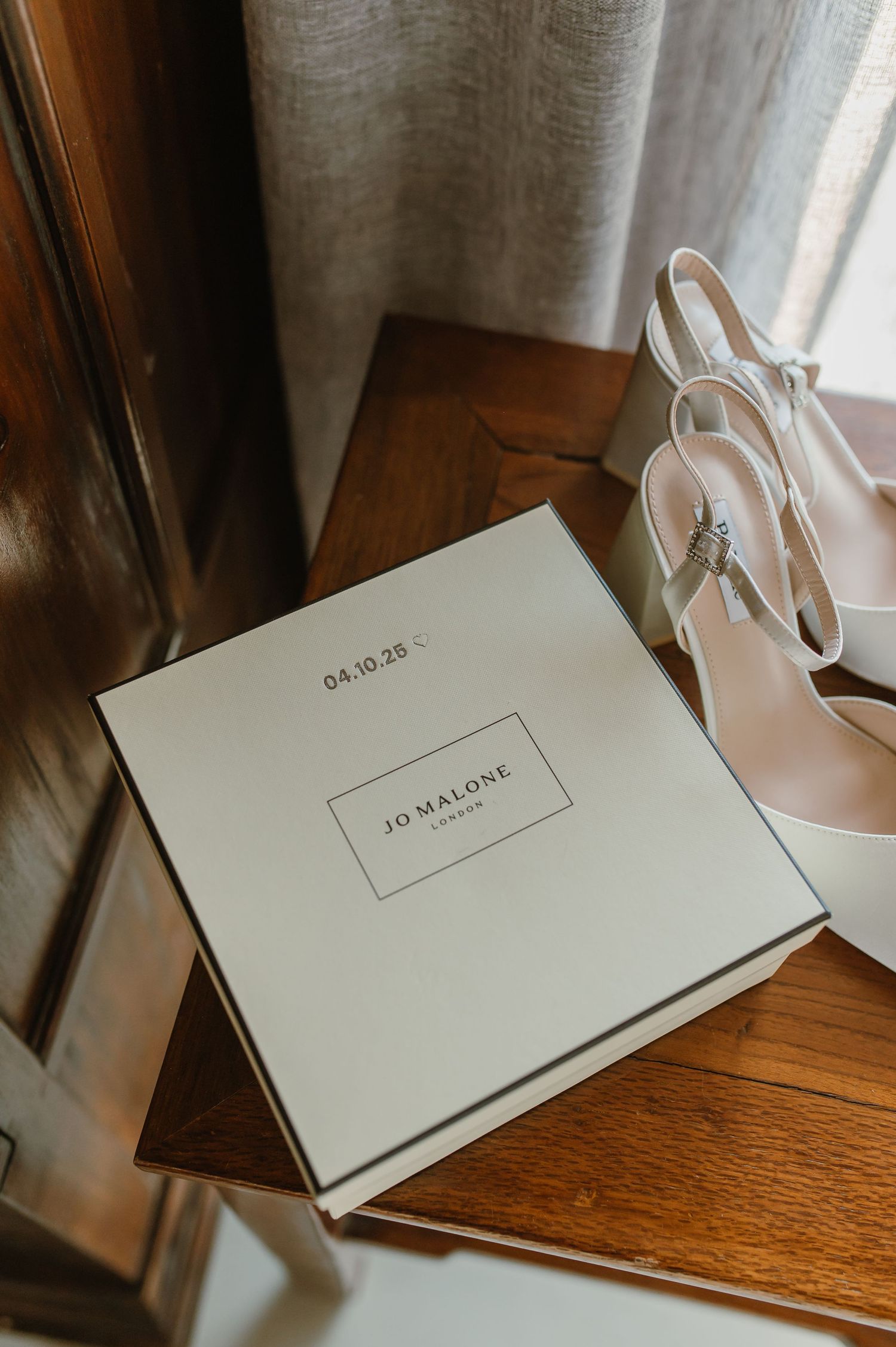 Jo Malone branded white gift boxes arranged on a wooden surface.