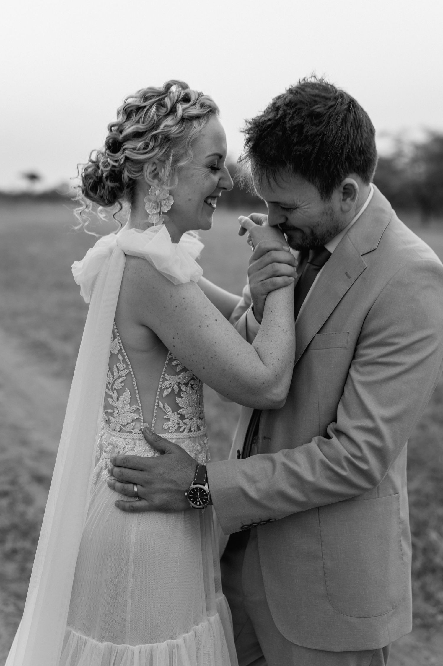 Tender black and white wedding photos show couple sharing romantic moments in a field.