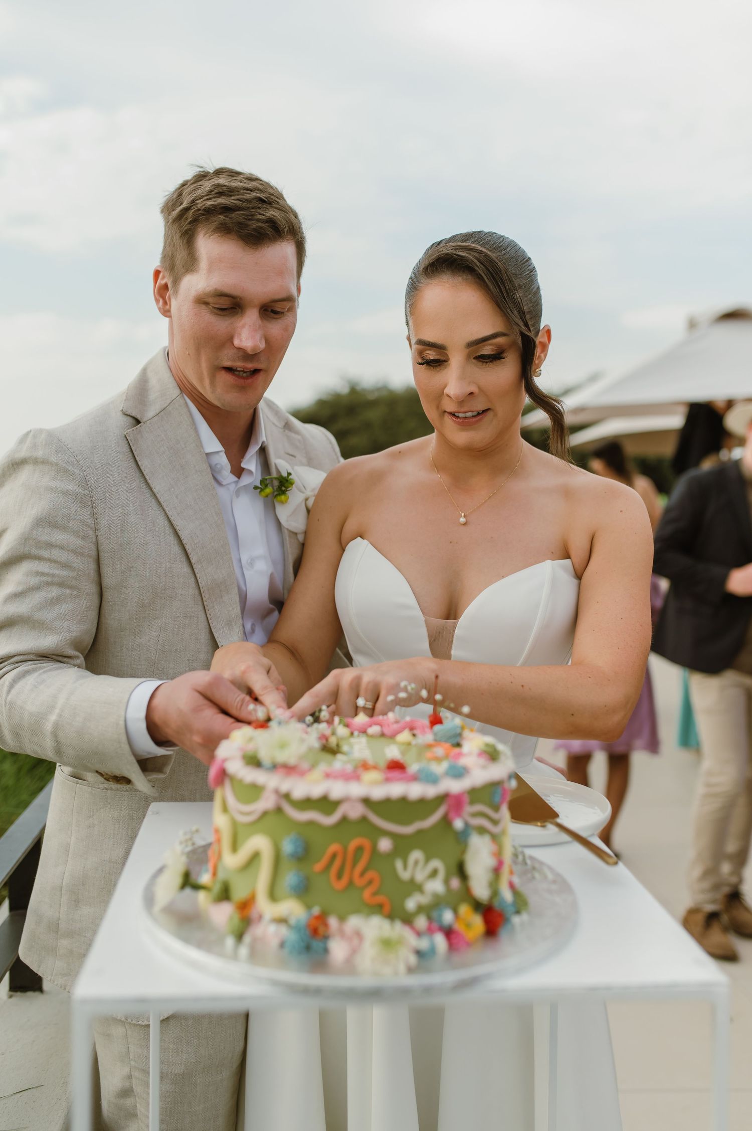 Wedding cake cutting moment at an outdoor celebration.