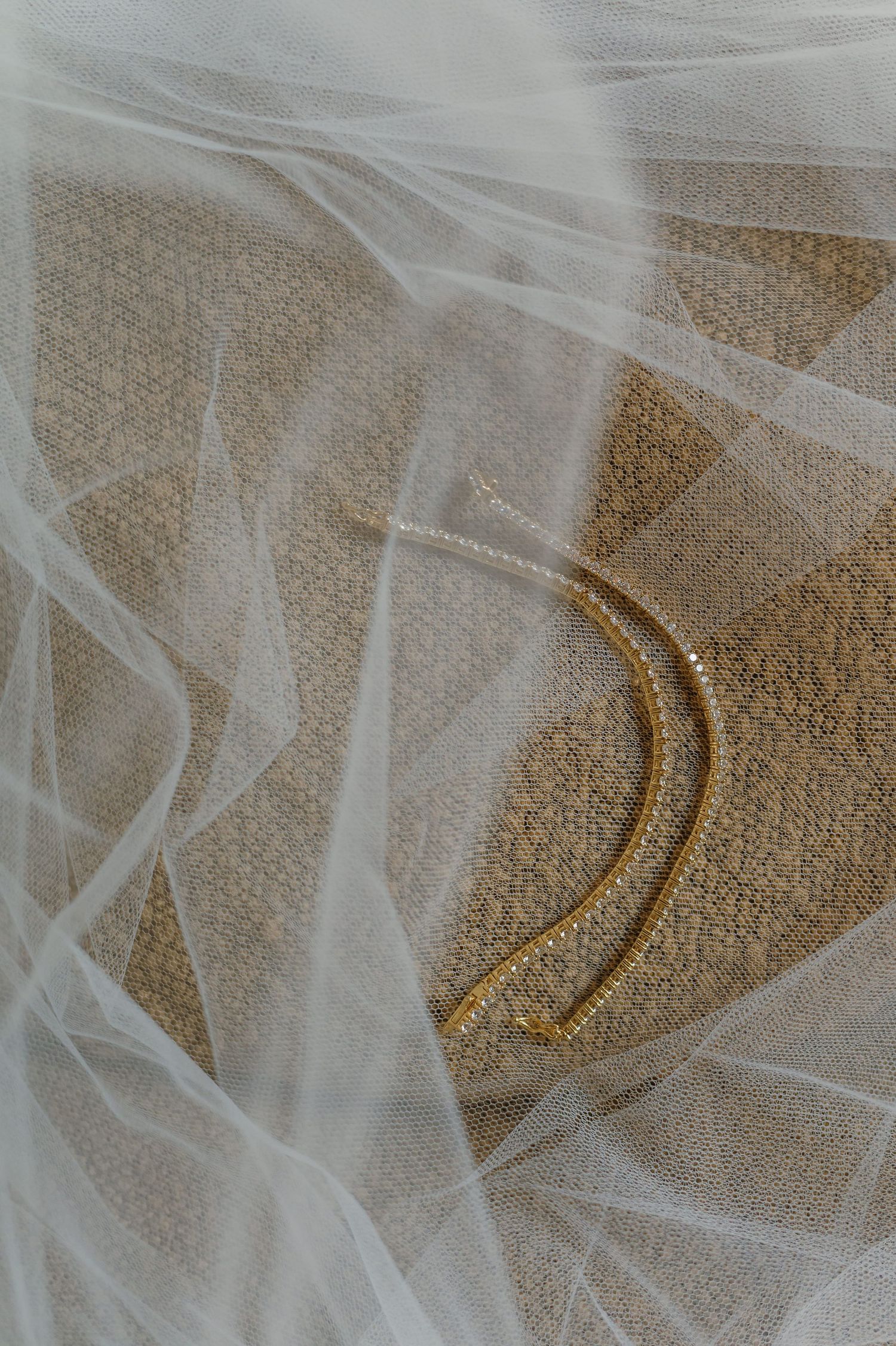 Gold curved hair pins resting on white tulle fabric for a bridal accessory flat lay.