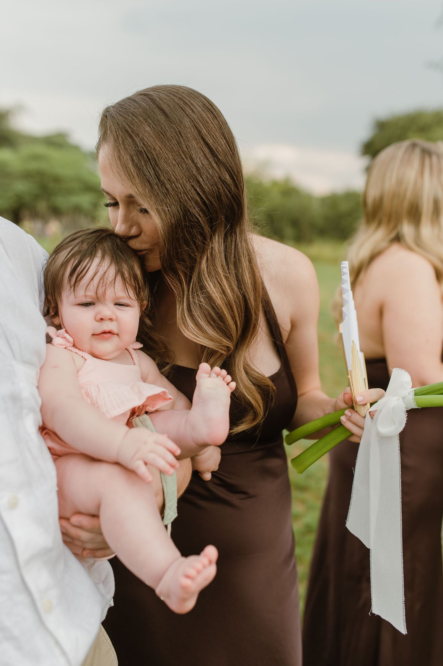 Close-up moments between wedding attendees in casual outdoor setting.