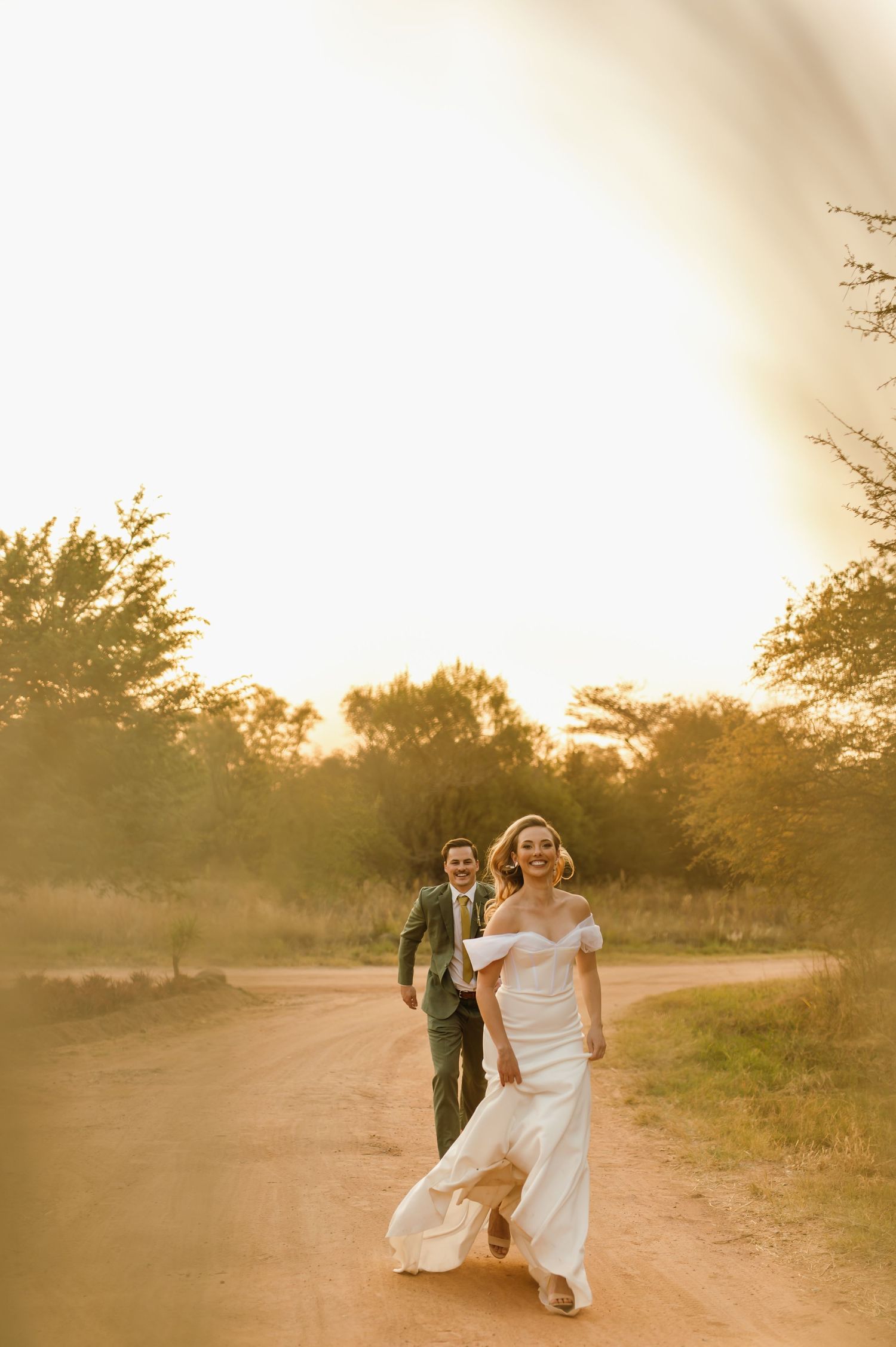 Wedding couple dancing in a golden sunlit field at sunset.