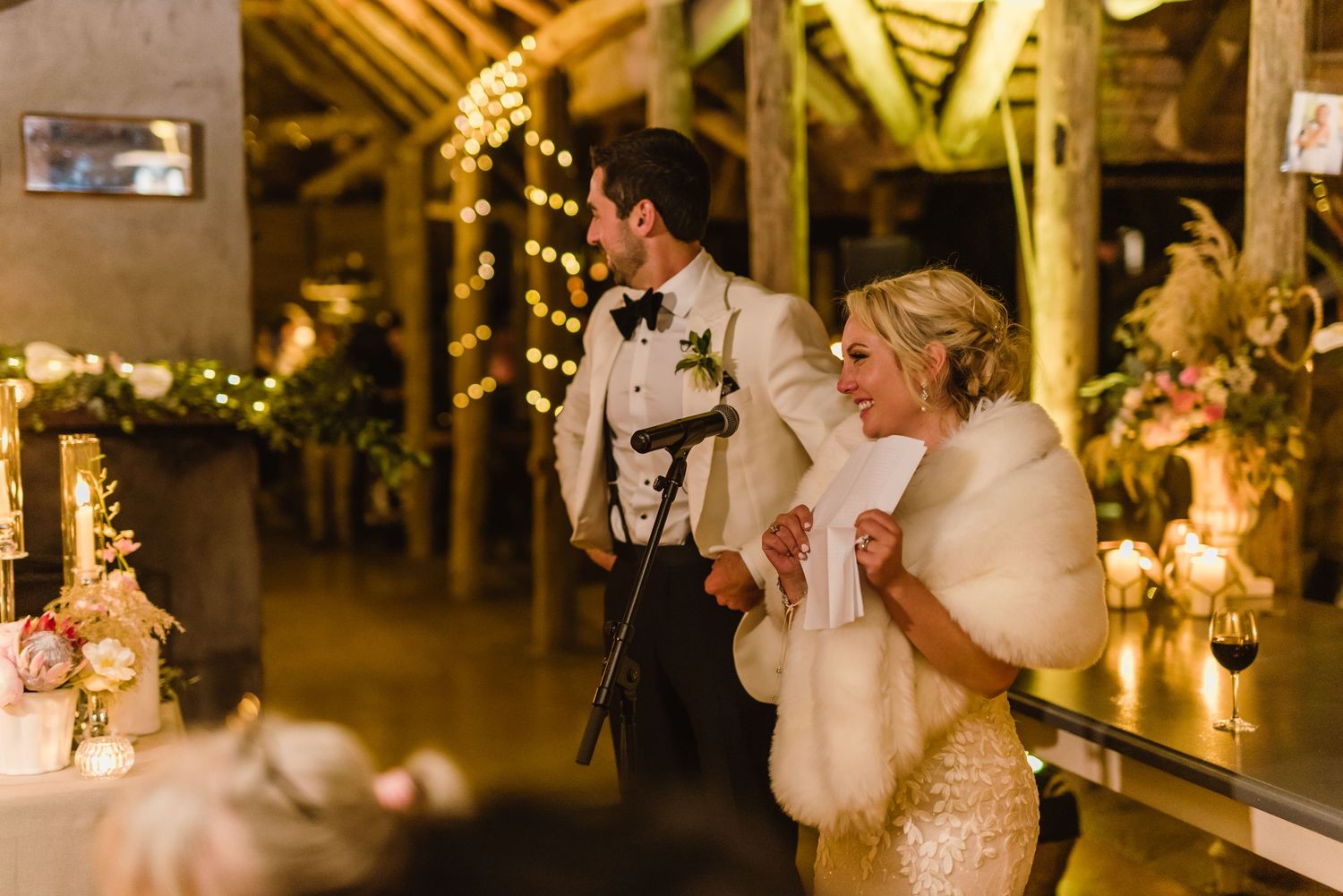 Wedding reception hall with festive lighting and guests celebrating at decorated dining tables.