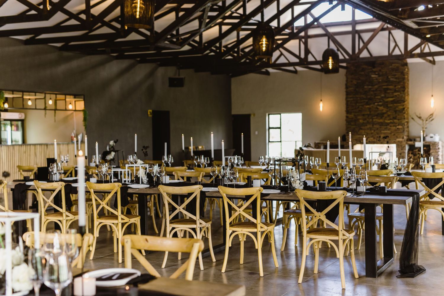Large reception hall with wooden chairs and industrial-style exposed ceiling beams.