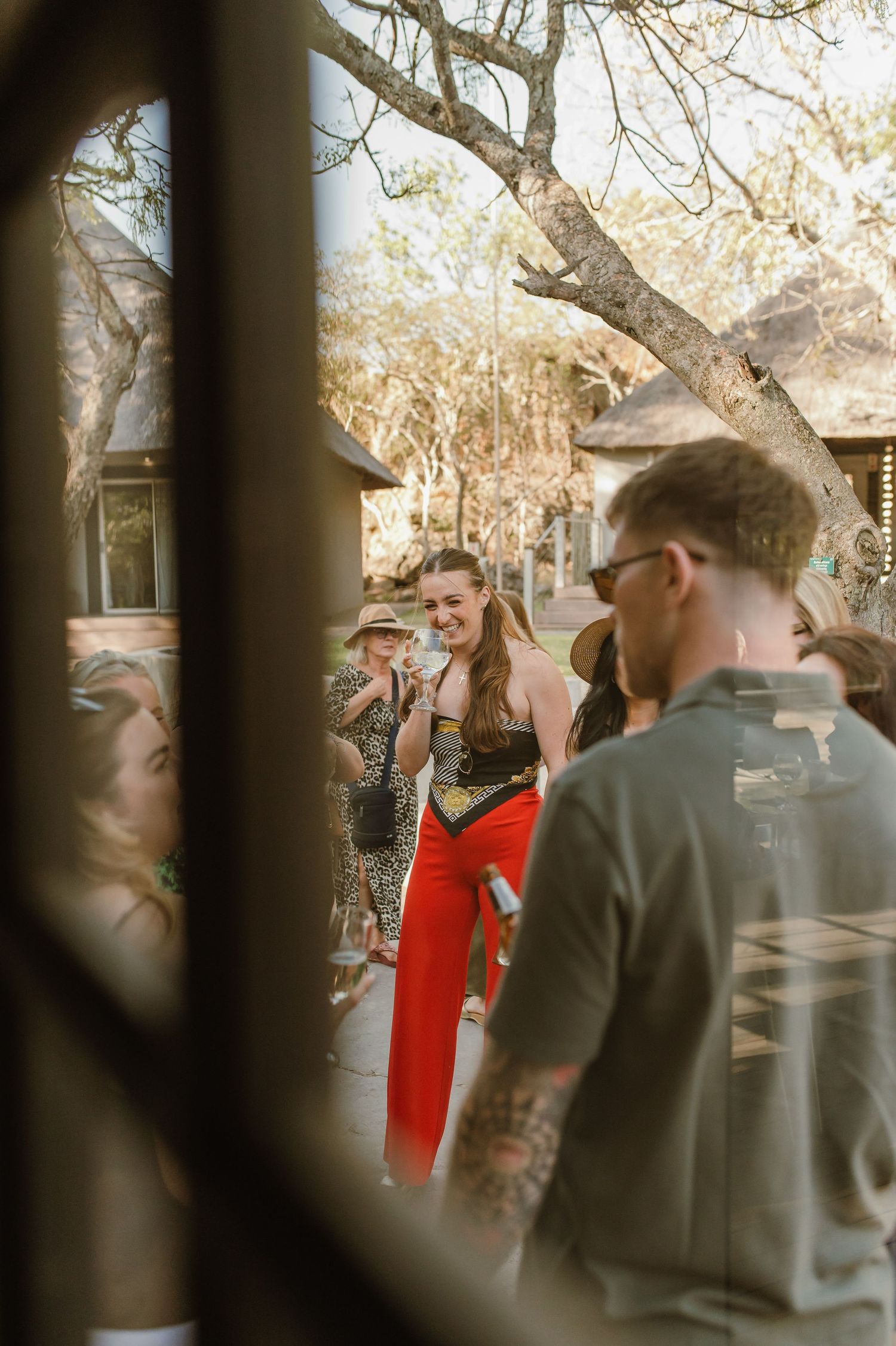 Outdoor social gathering through window frames at a safari lodge.