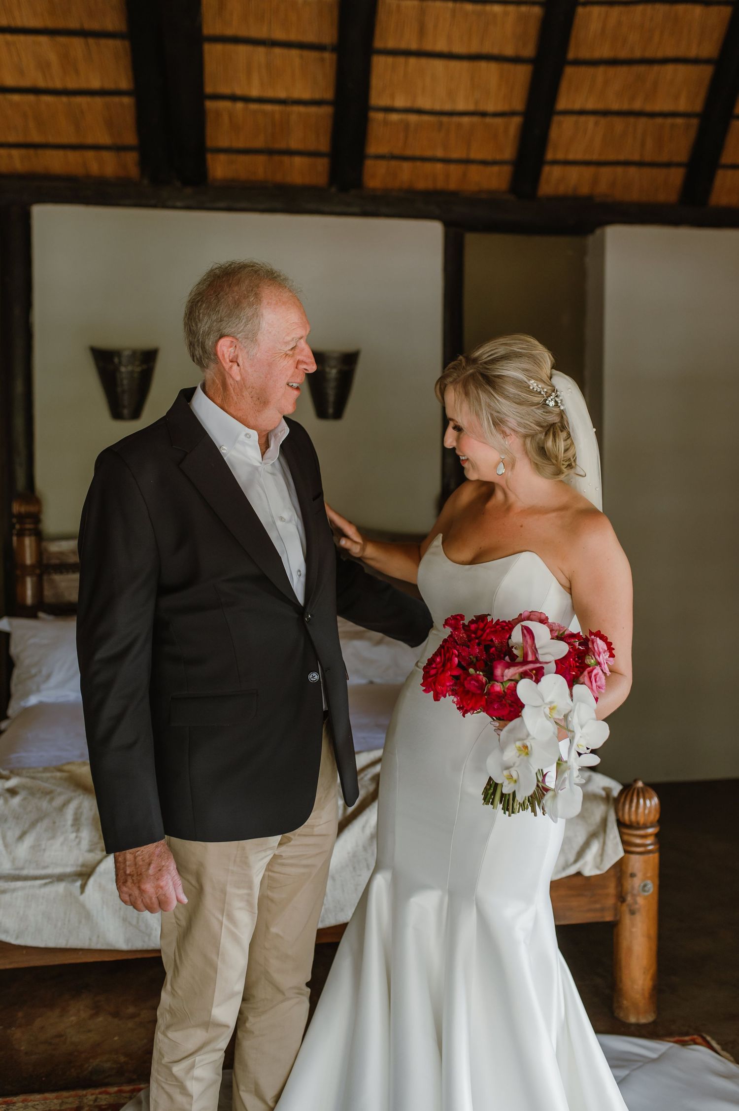 Candid interaction in a rustic room with thatched ceiling and wooden furniture.