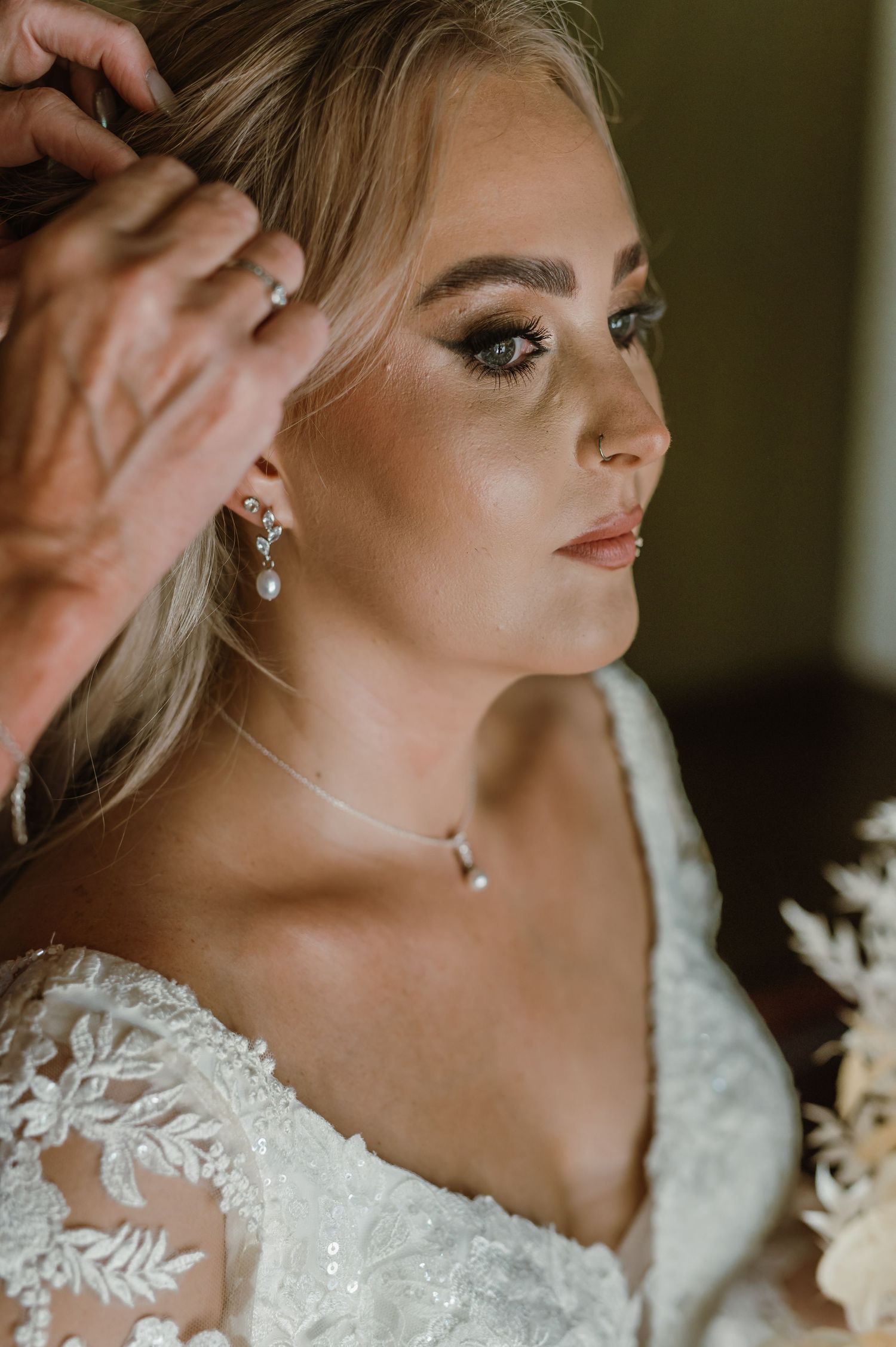 Close-up bridal portrait showing elegant jewelry and detailed makeup.