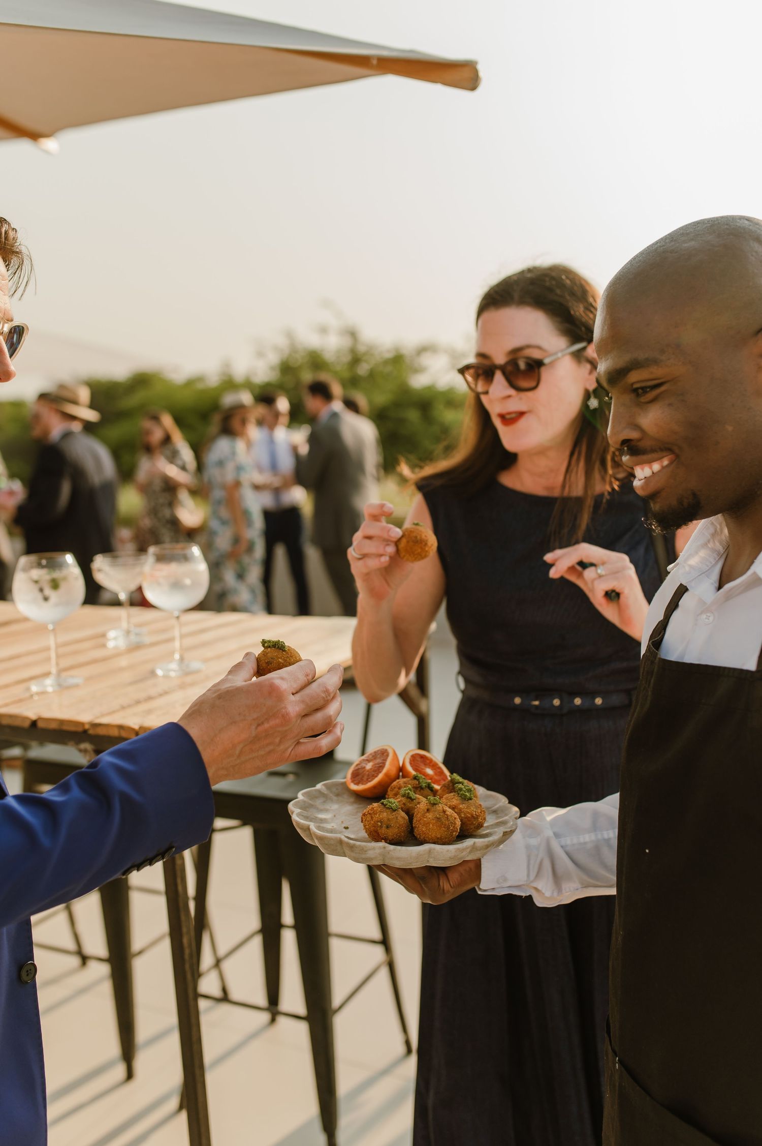 Guests enjoying appetizers and drinks at an elegant outdoor cocktail reception.