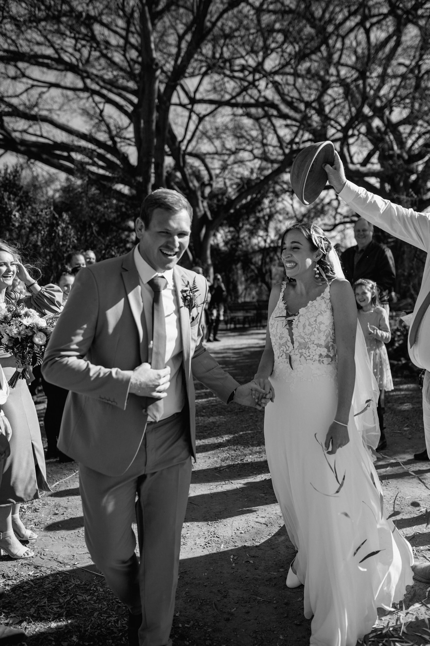 Wedding celebration in black and white showing joyful moments under ancient trees.
