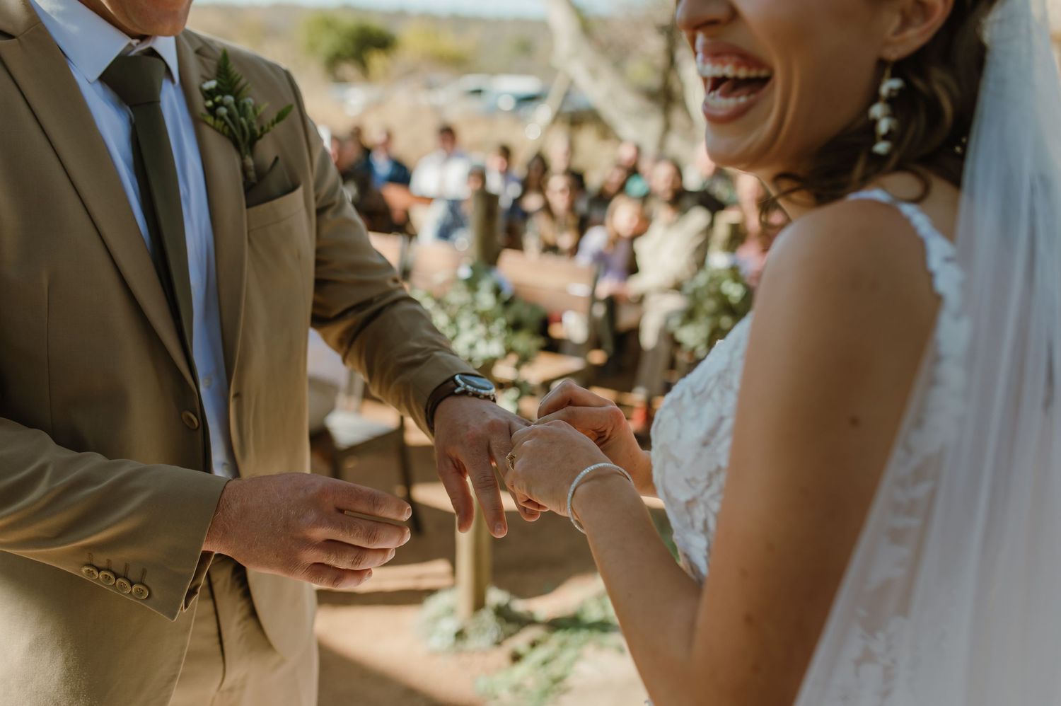 Couple laughs together during their outdoor wedding ceremony under desert skies.
