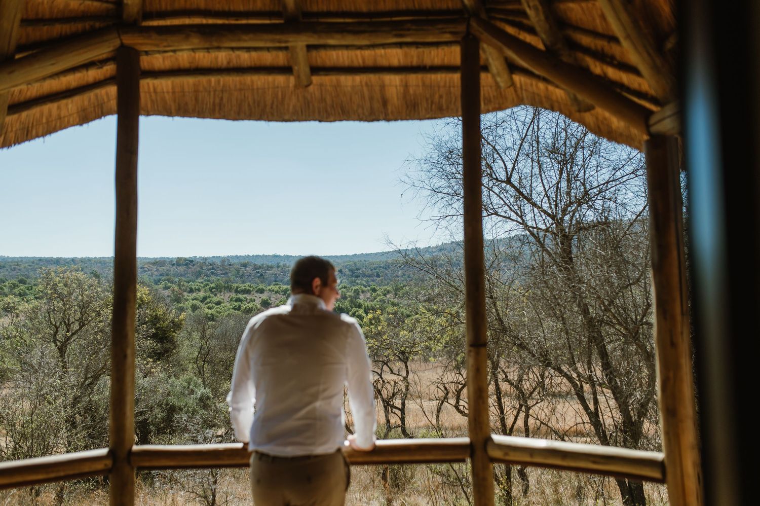 View from inside a thatched-roof gazebo overlooking a scenic landscape.