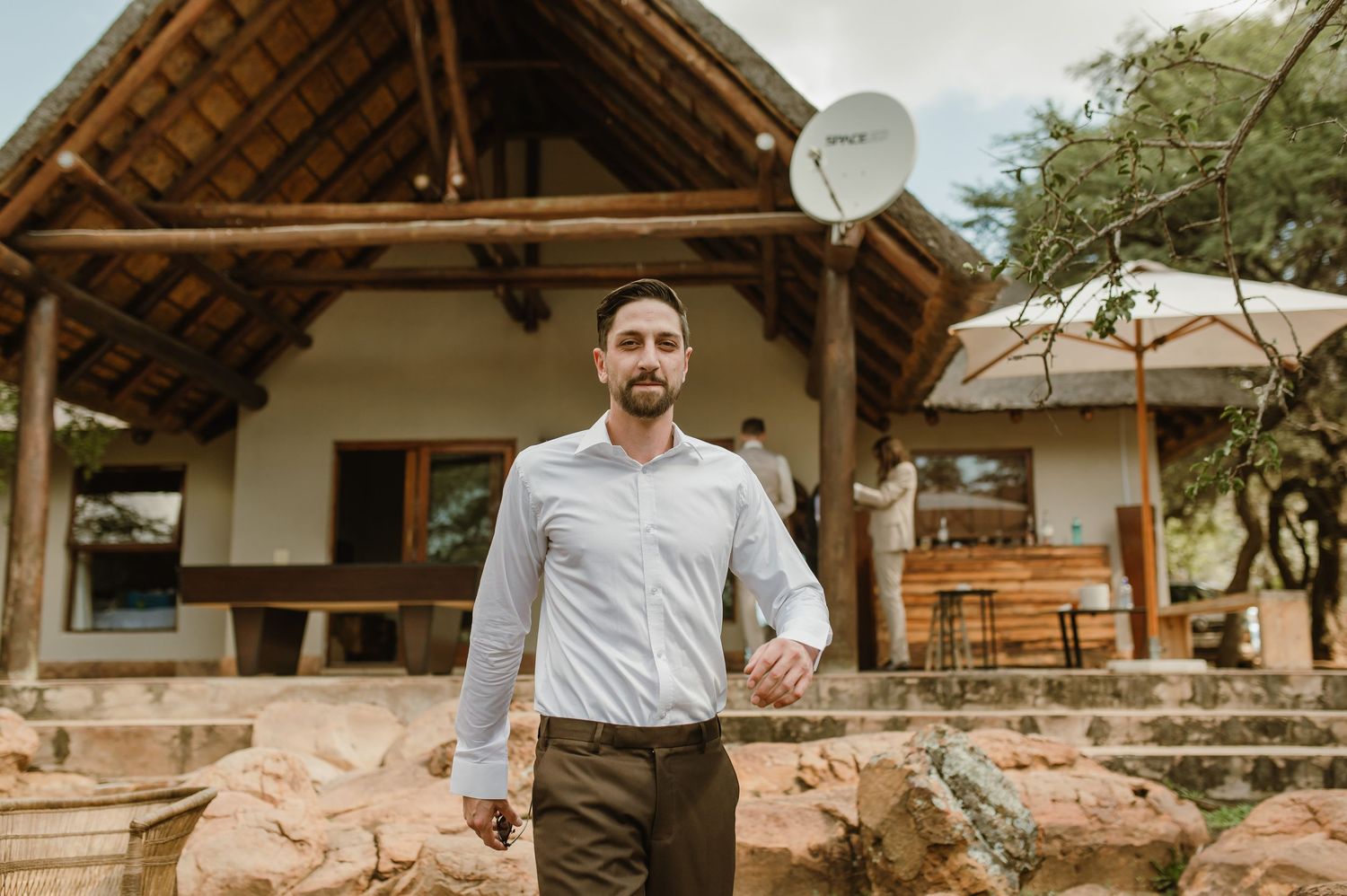 Rustic lodge exterior with thatched roof and stone walls in natural surroundings.