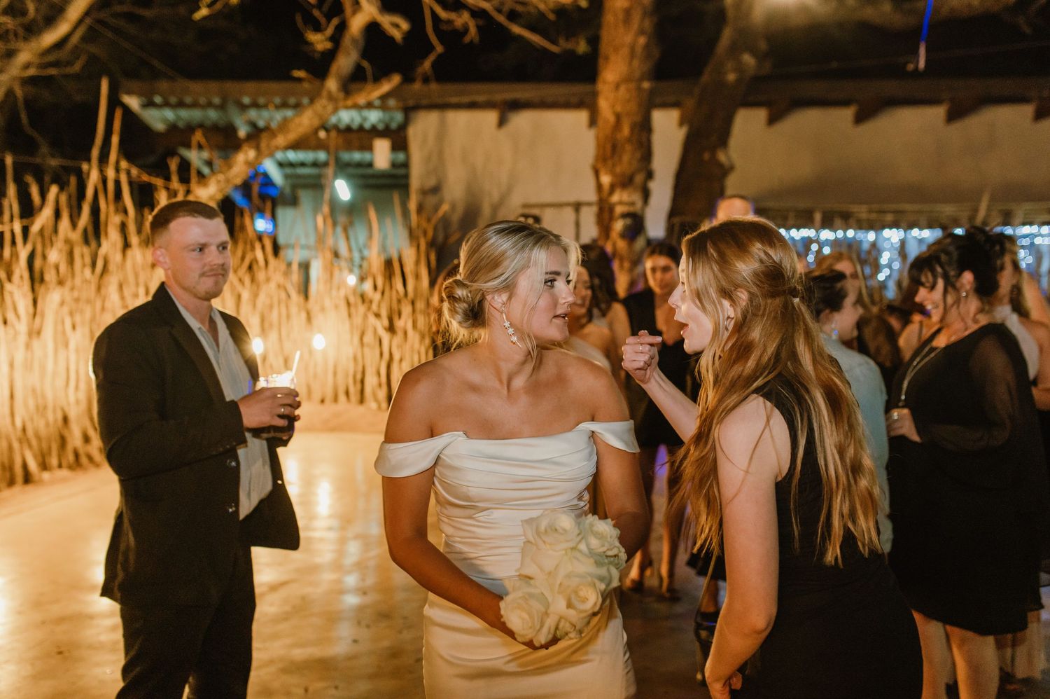 Wedding celebration in a rustic venue with thatched roof and warm ambient lighting.