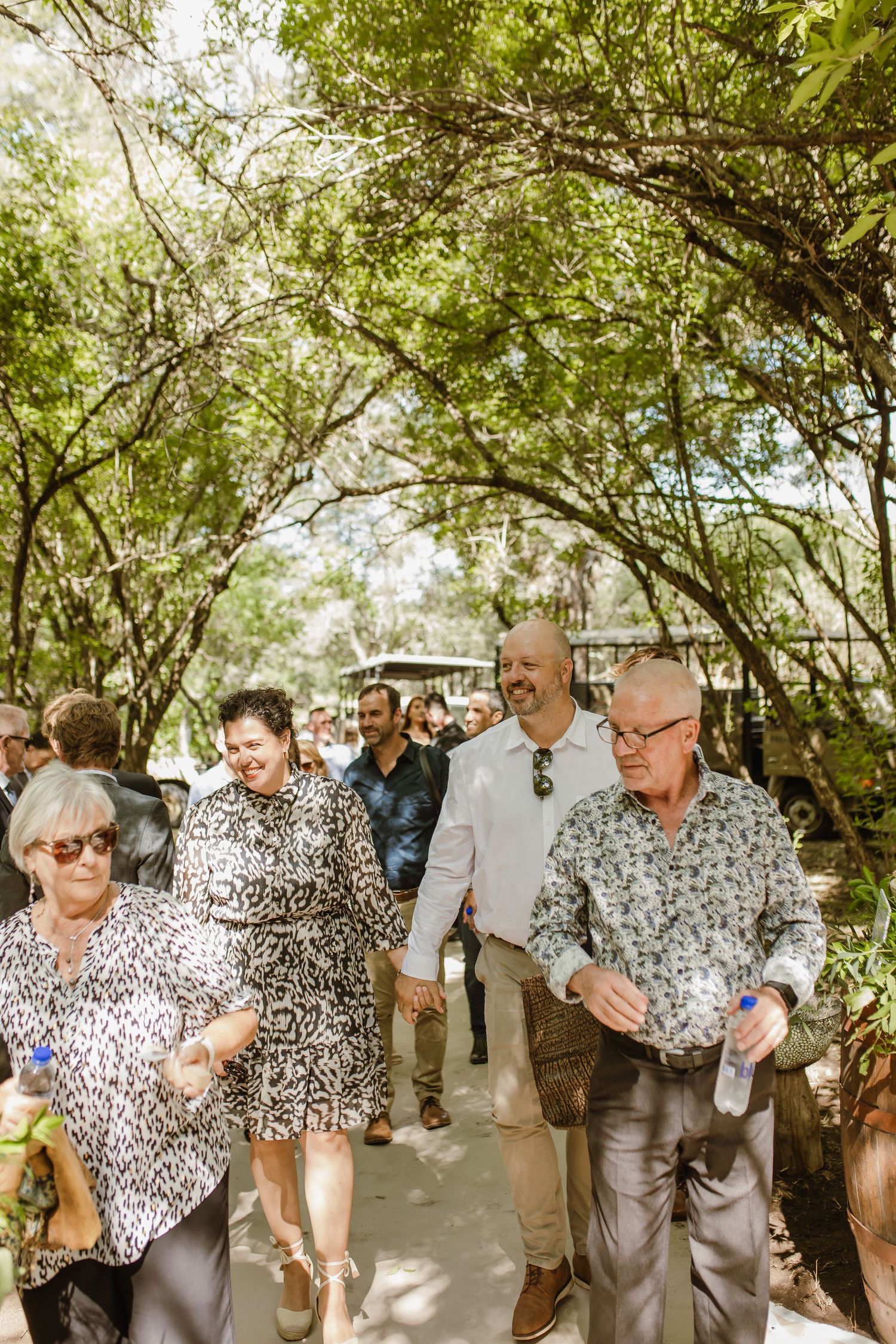 Group of guests in matching leopard print shirts celebrate at an outdoor wedding.