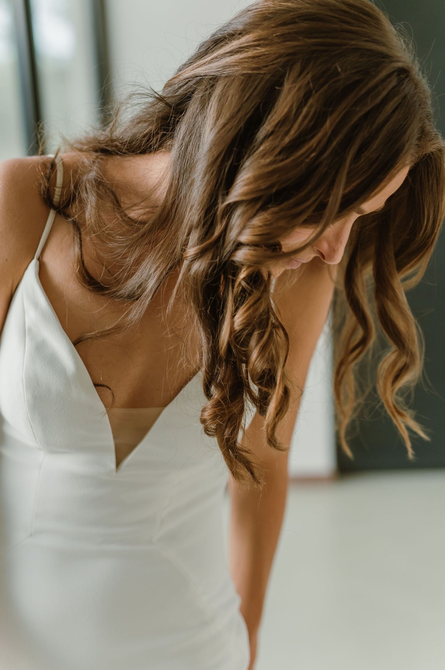 A candid moment showing someone in a sleeveless white dress leaning forward with natural hair movement.