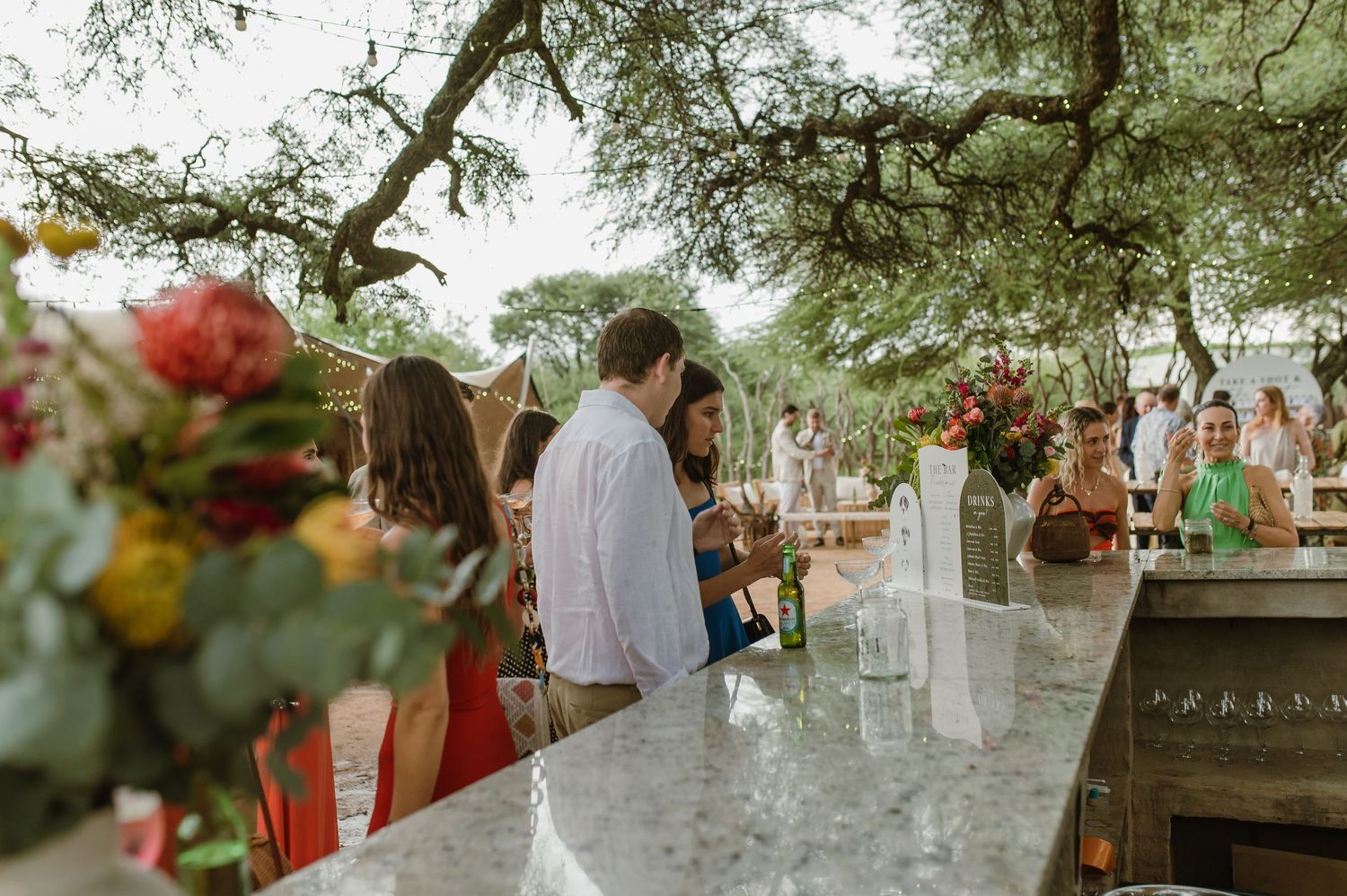 Elegant outdoor bar setup with floral arrangements and drink menus.
