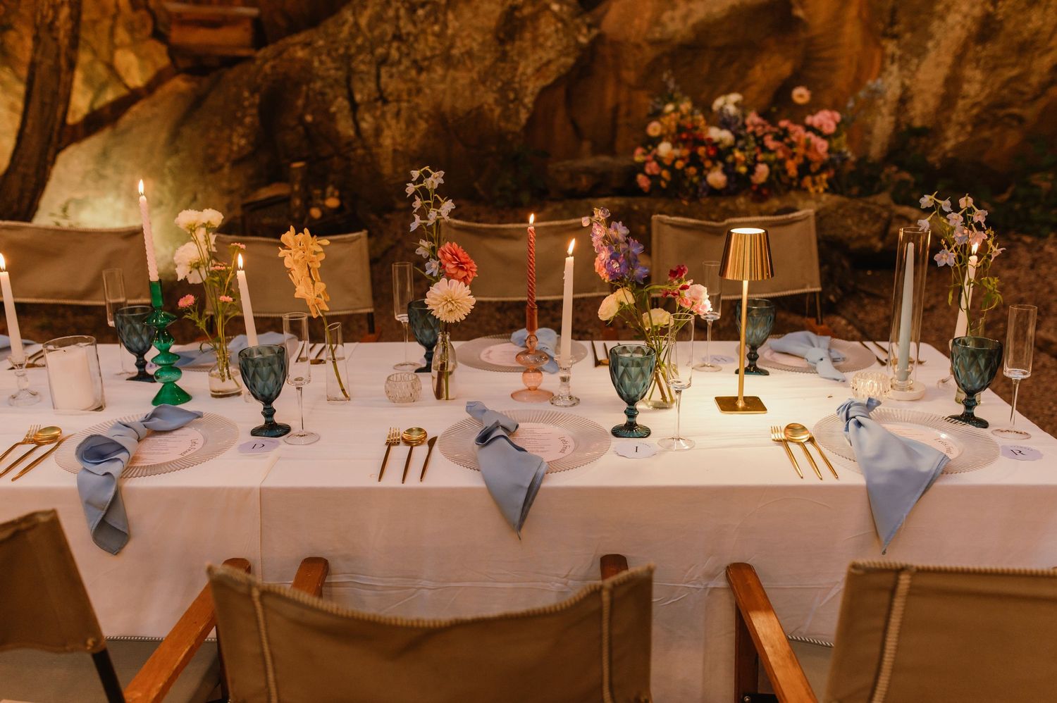 Elegant wedding reception table with colorful goblets, candles, and floral centerpieces.