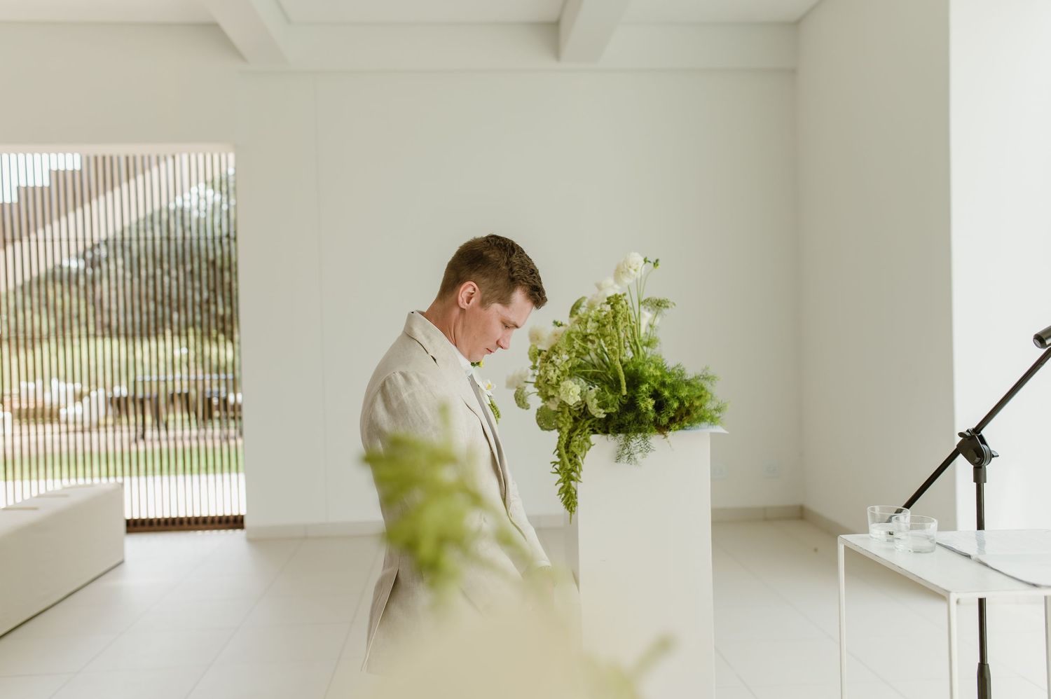 Bright modern interior with white beams and walls featuring green plants and minimalist decor elements.