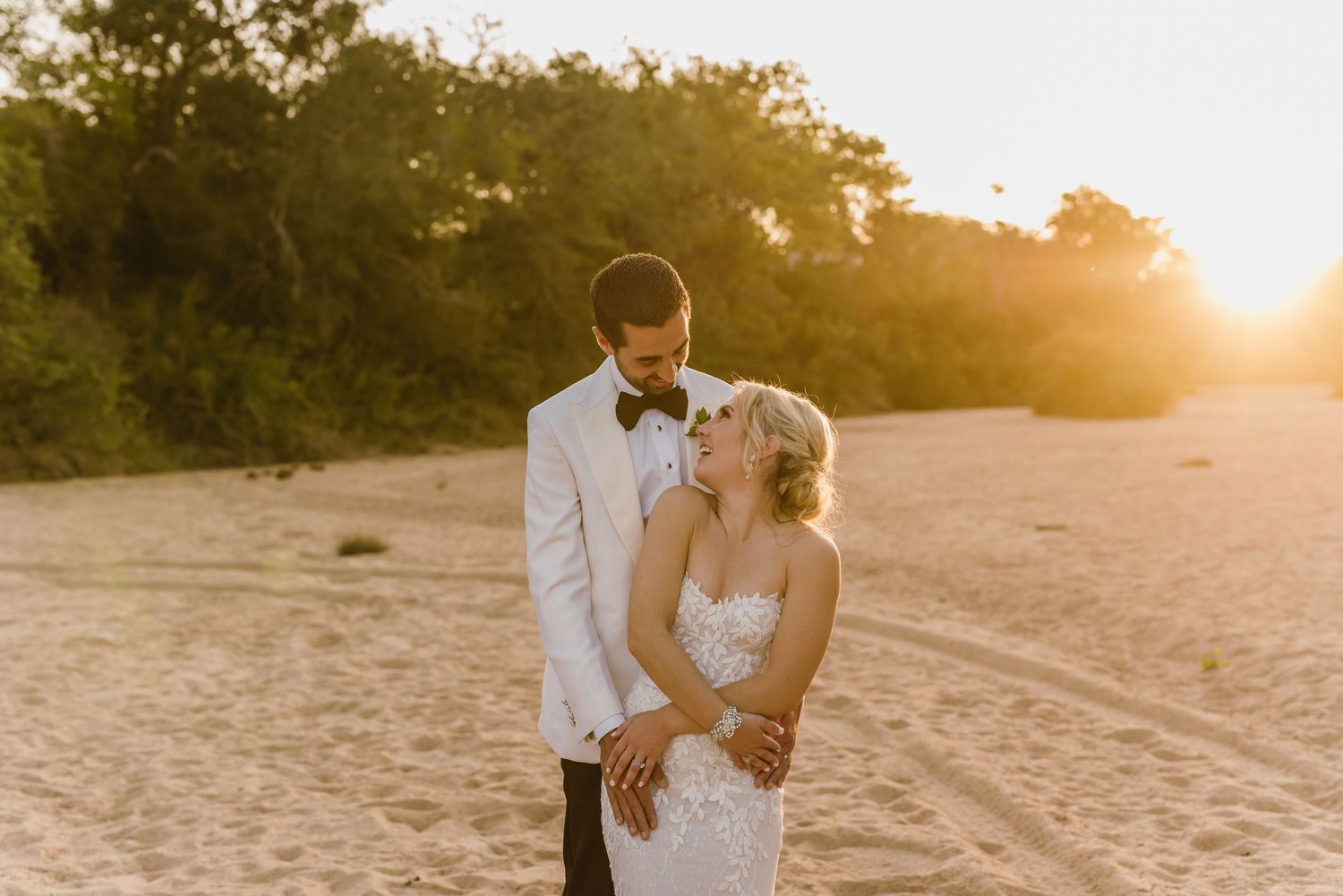 Newlyweds share intimate moments on sandy beach during golden hour.