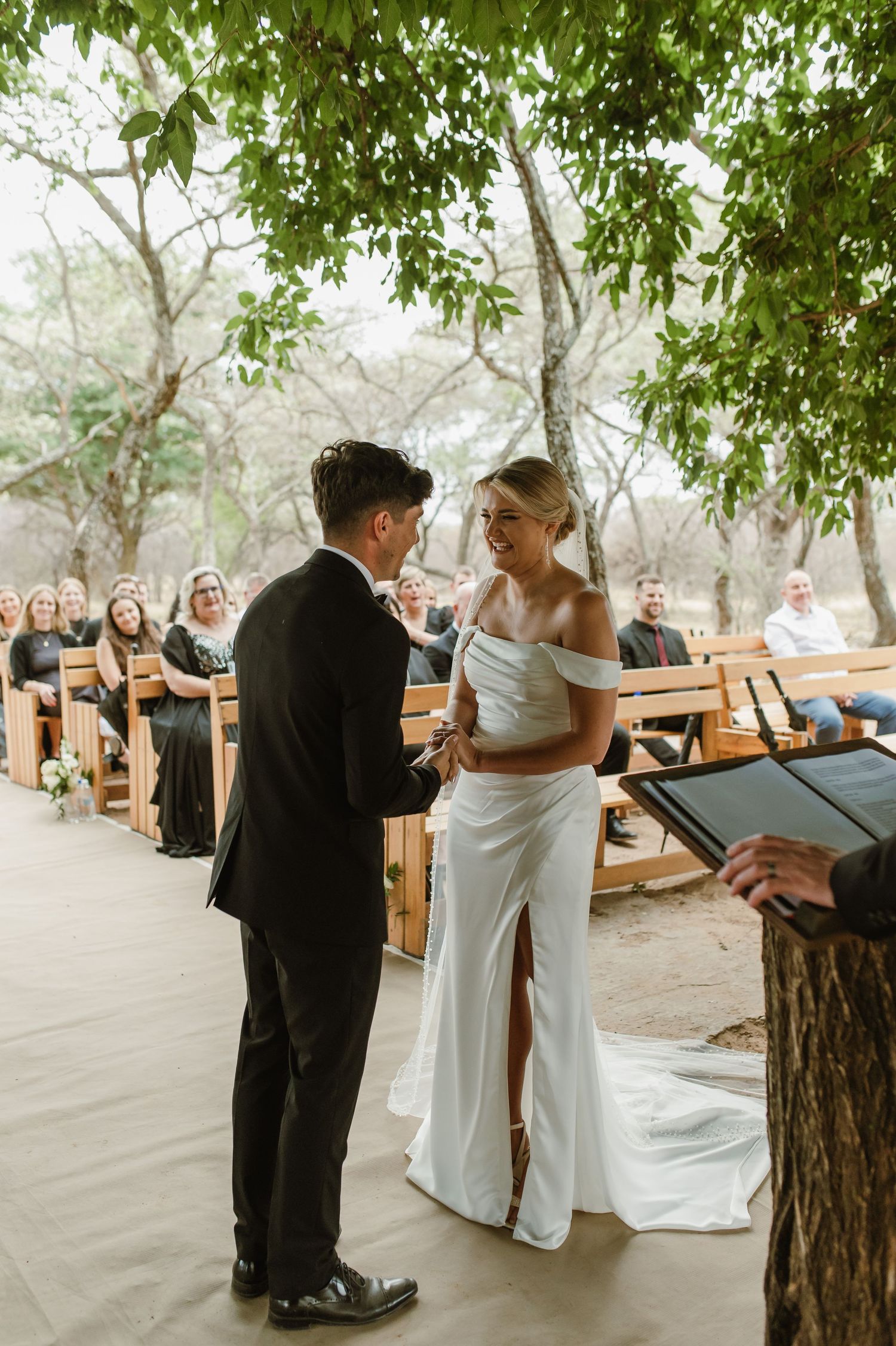 Couple shares a candid moment during their outdoor wedding ceremony surrounded by nature.