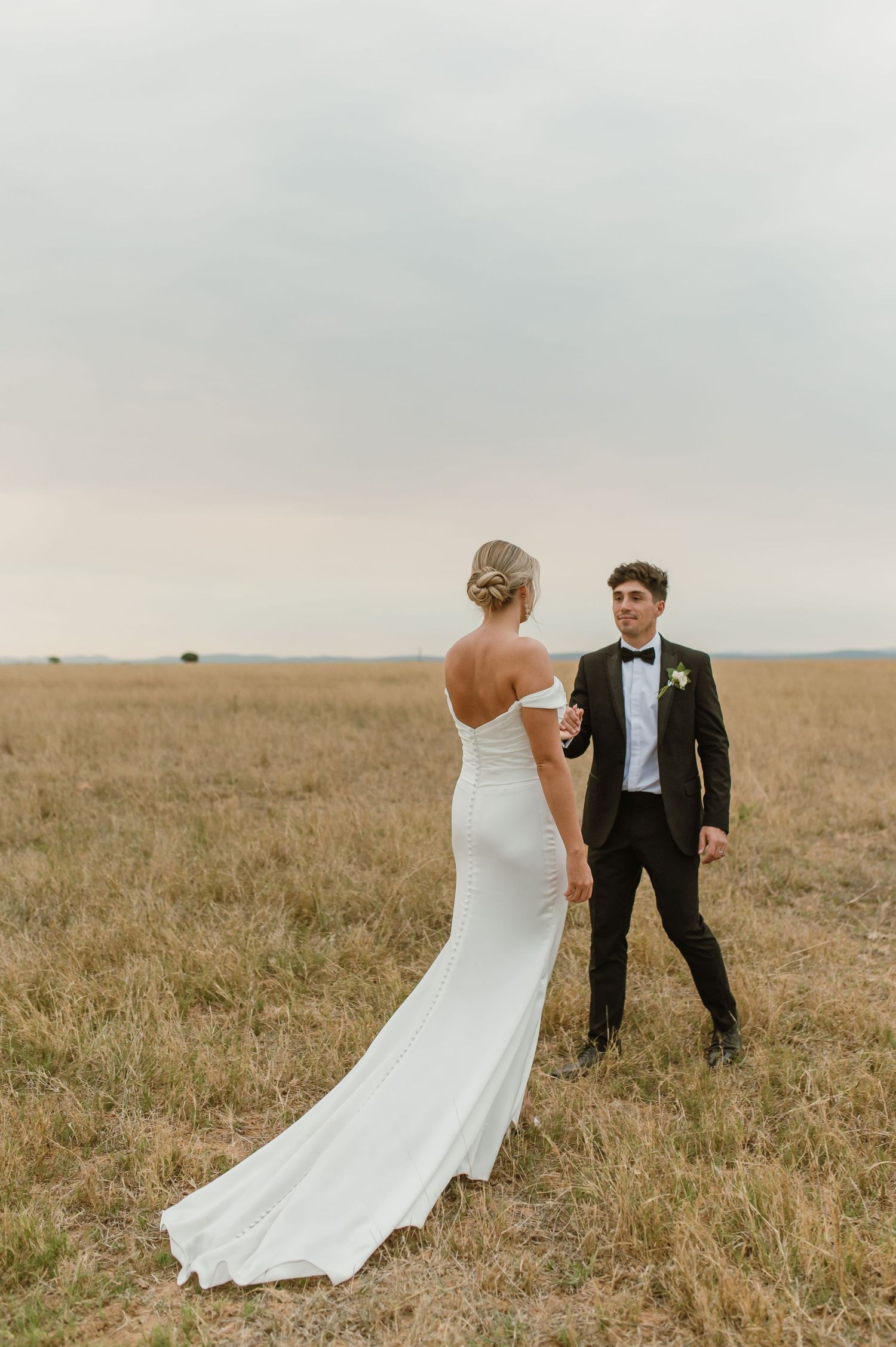 Wedding couple walking and posing in natural grassland setting.