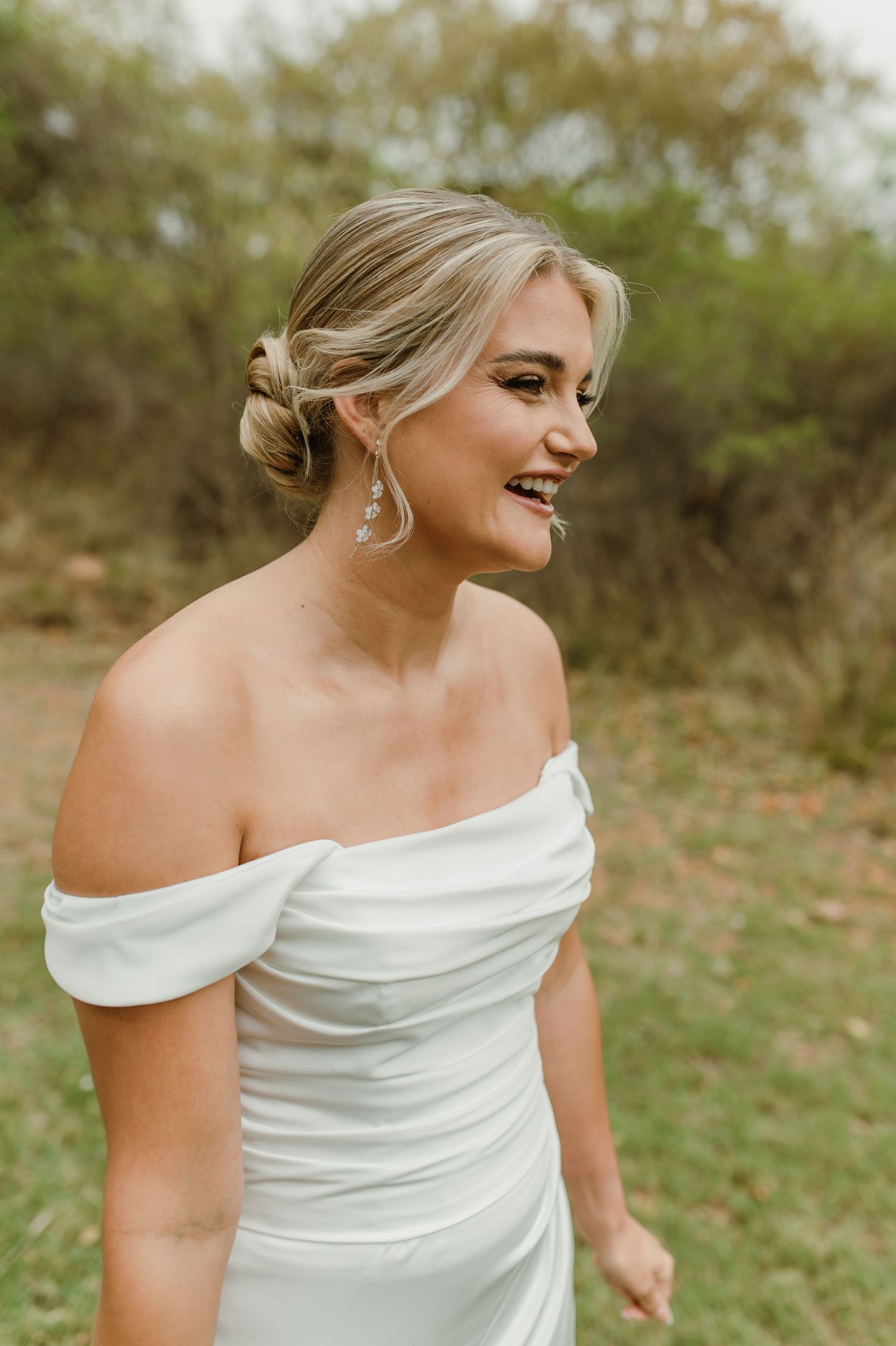 Candid bridal portrait featuring off-shoulder gown and statement earrings.