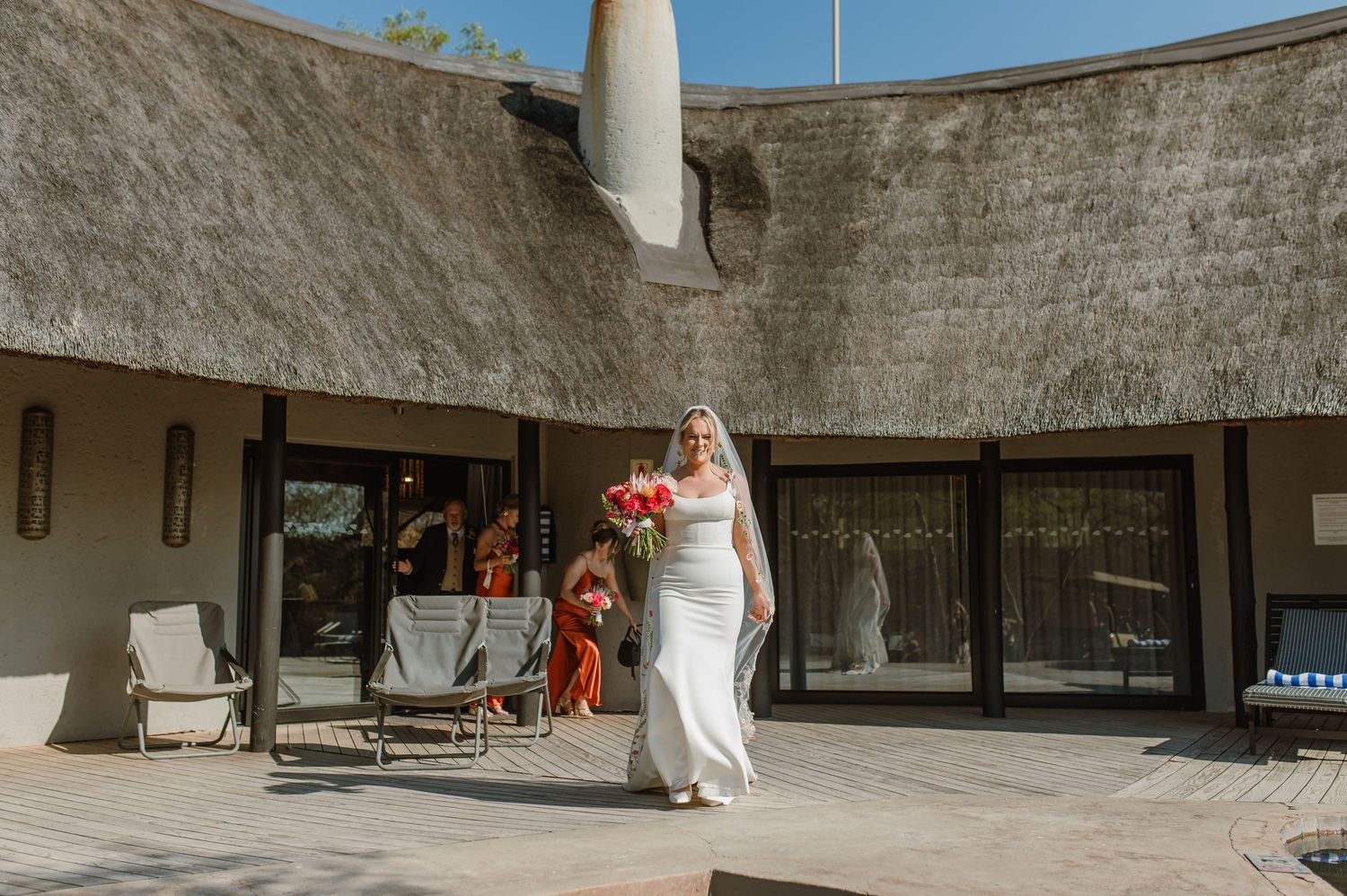 Panoramic view of a thatched roof safari lodge with stone walls.