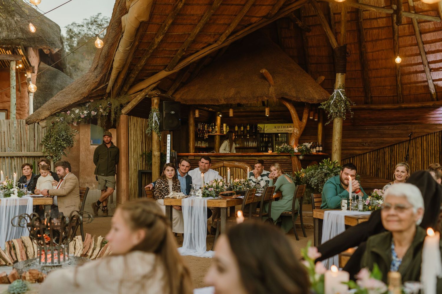 Rustic barn interior decorated for a wedding reception with wooden beams and ambient lighting.